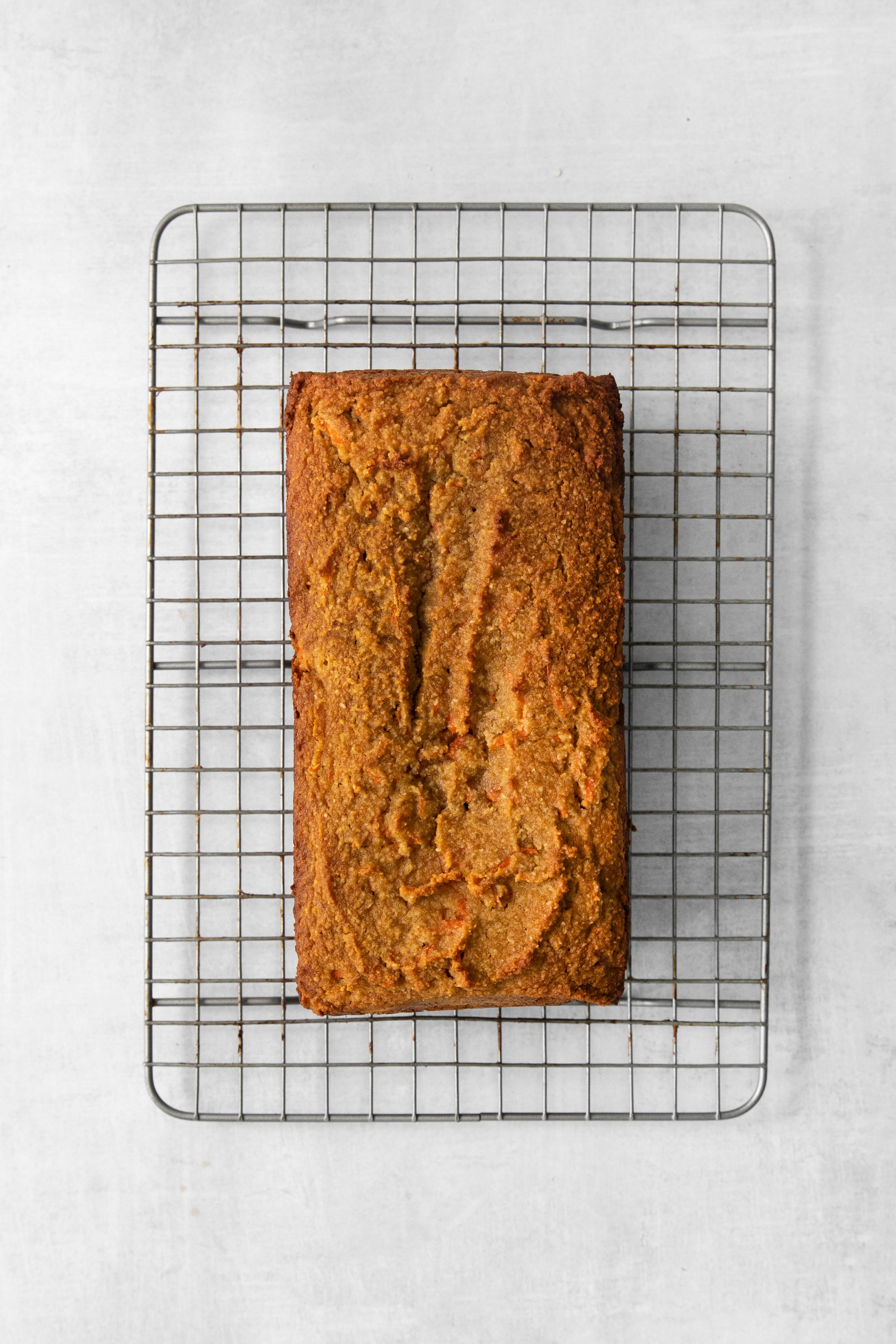overhead of a baked carrot cake loaf on a cooling rack.