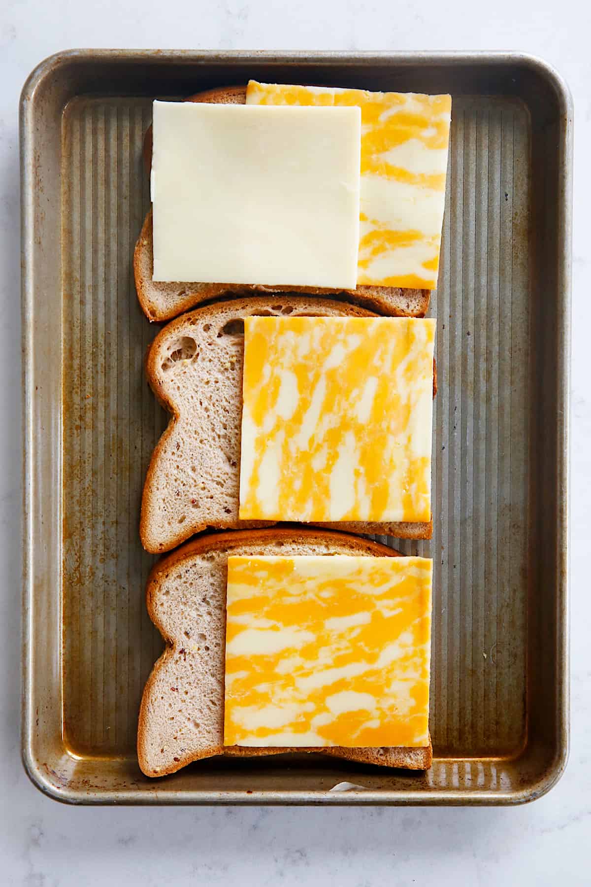 cheese being layered onto a sandwich.