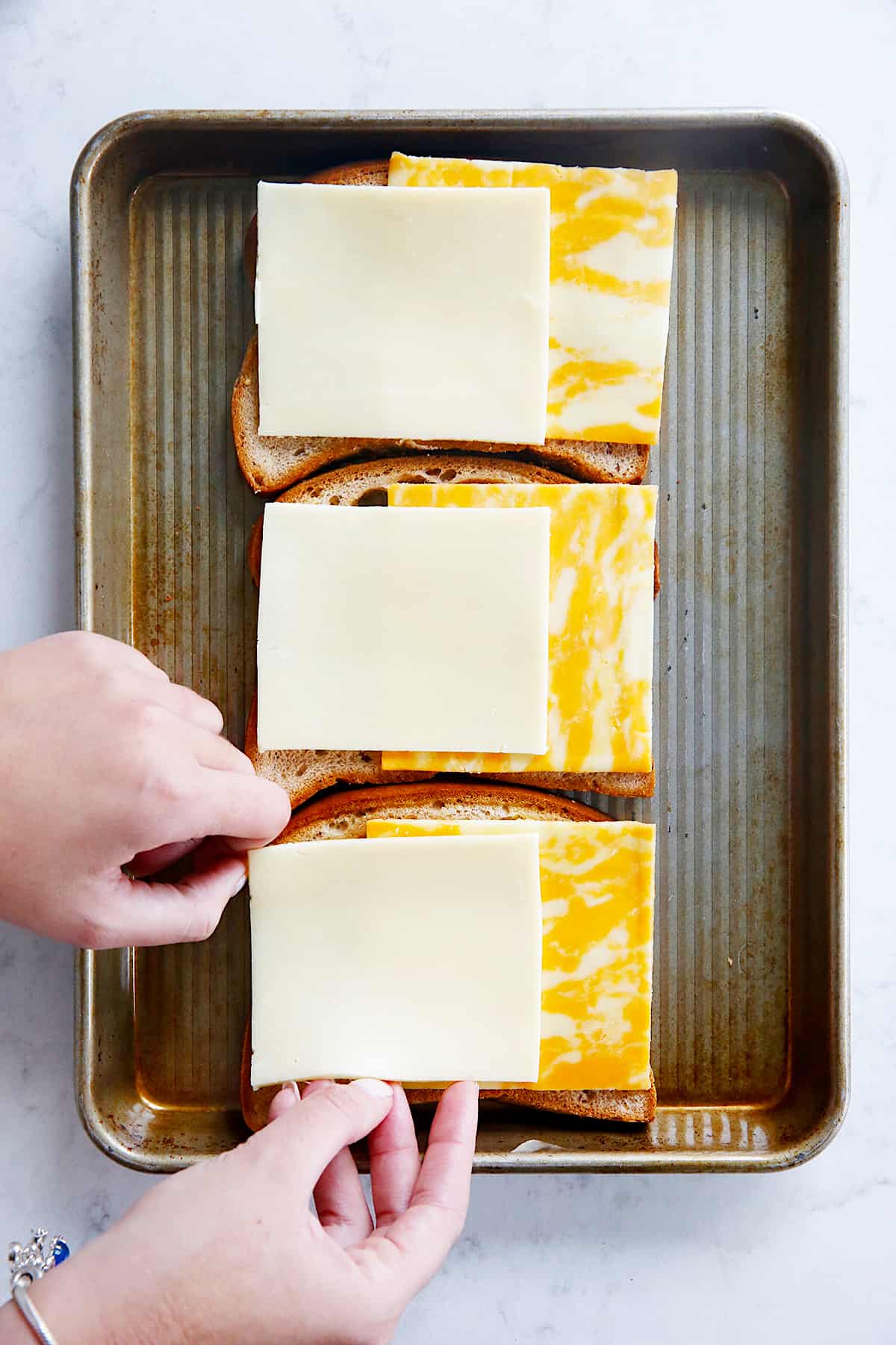 cheese being layered onto a sandwich.