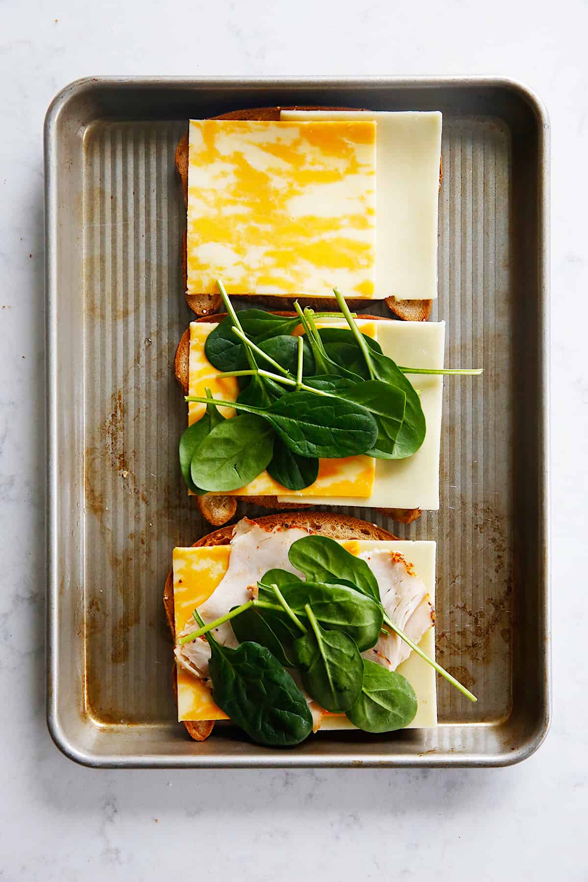 spinach being layered onto a sandwich.