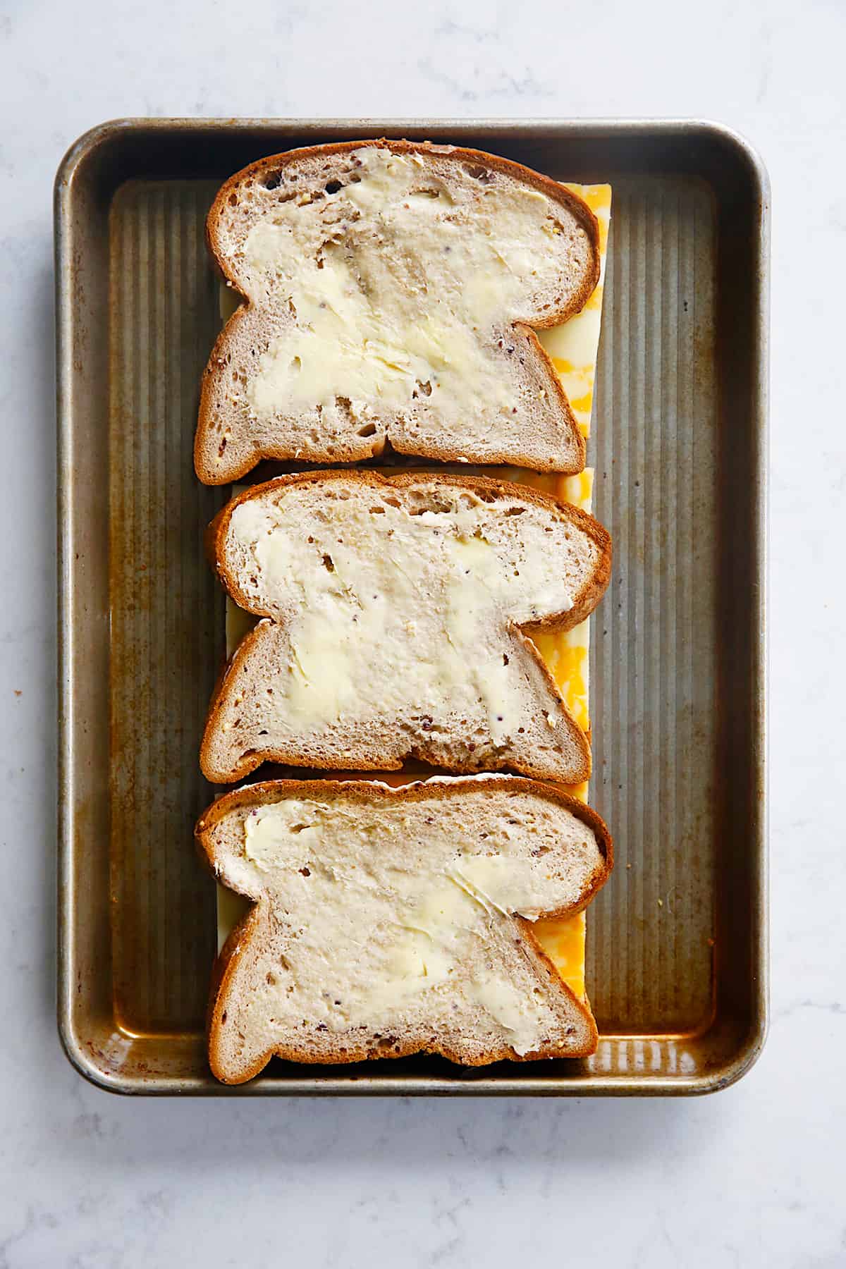 unbaked cheese sandwiches on a sheet pan.