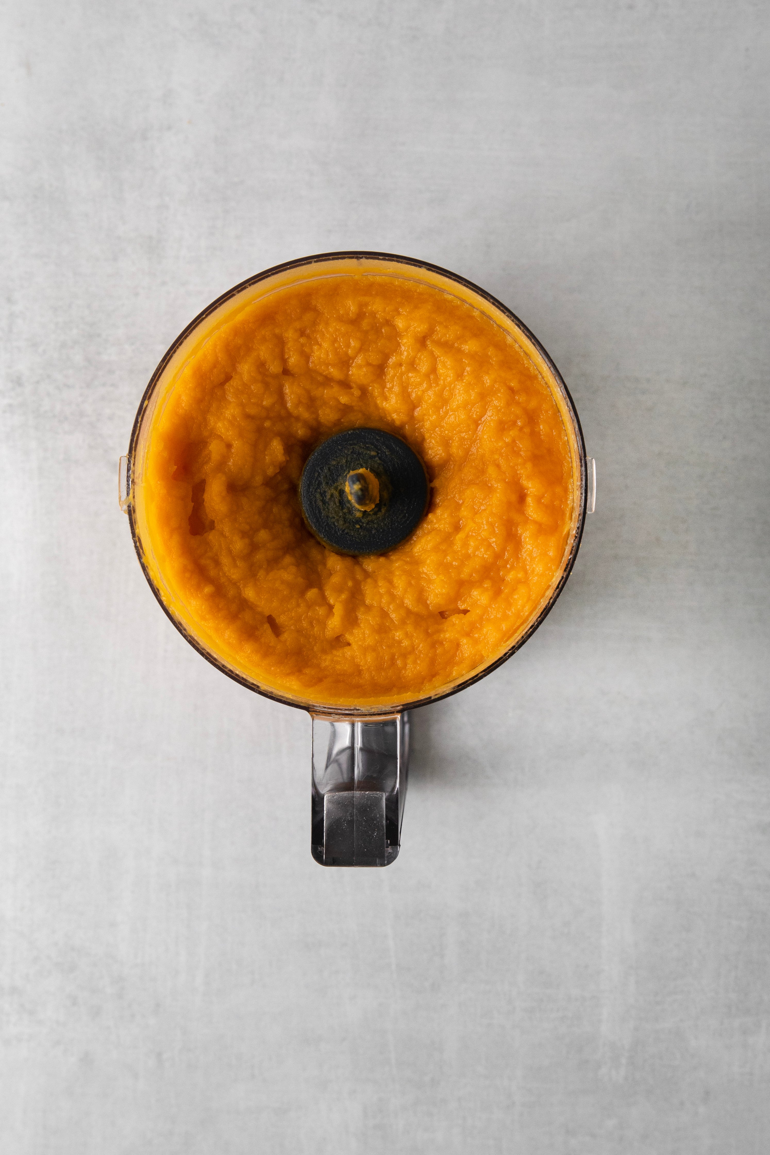 a food processor with mashed sweet potatoes.