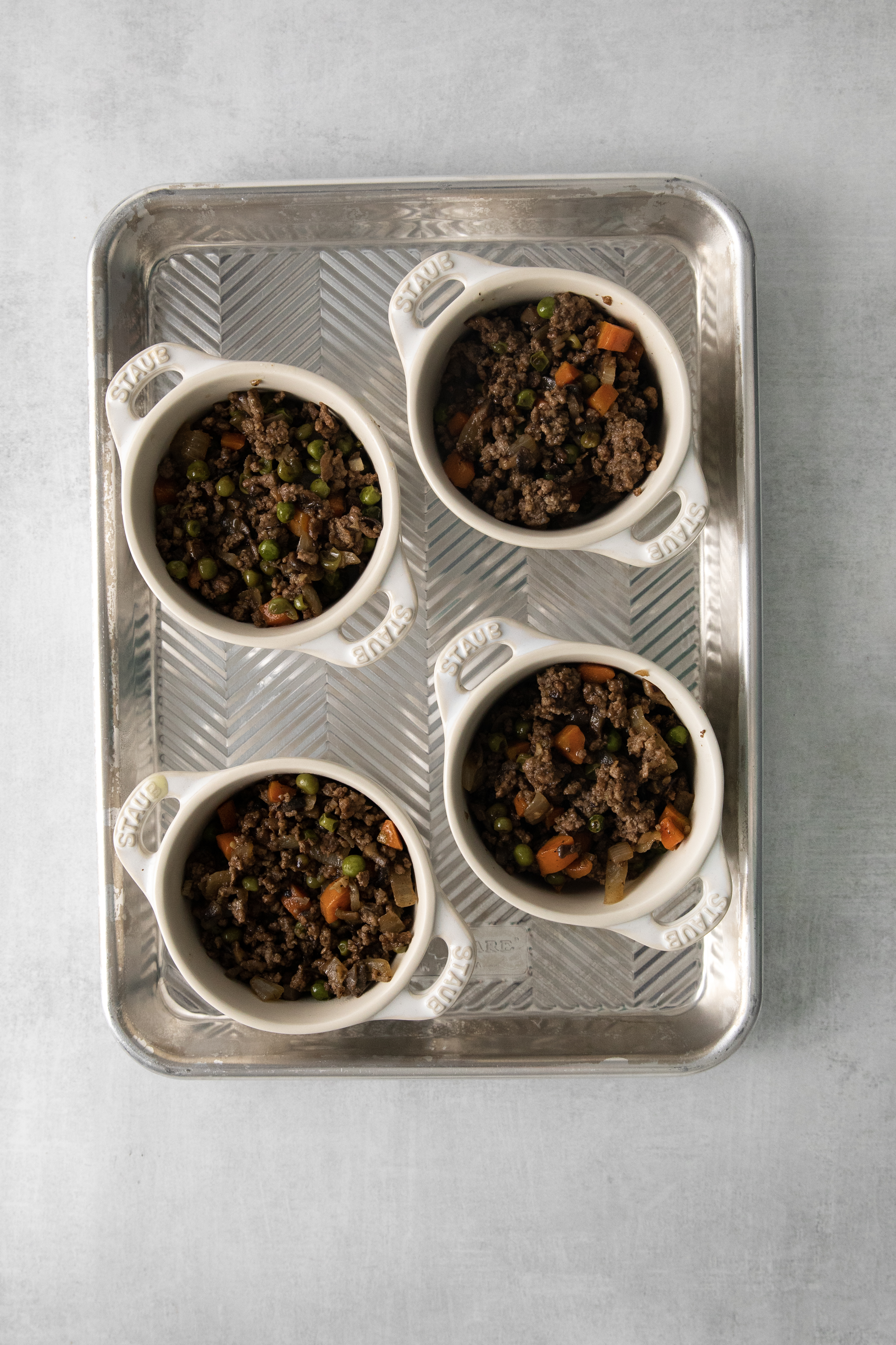 four bowls on a baking sheet filled with ground beef filling.