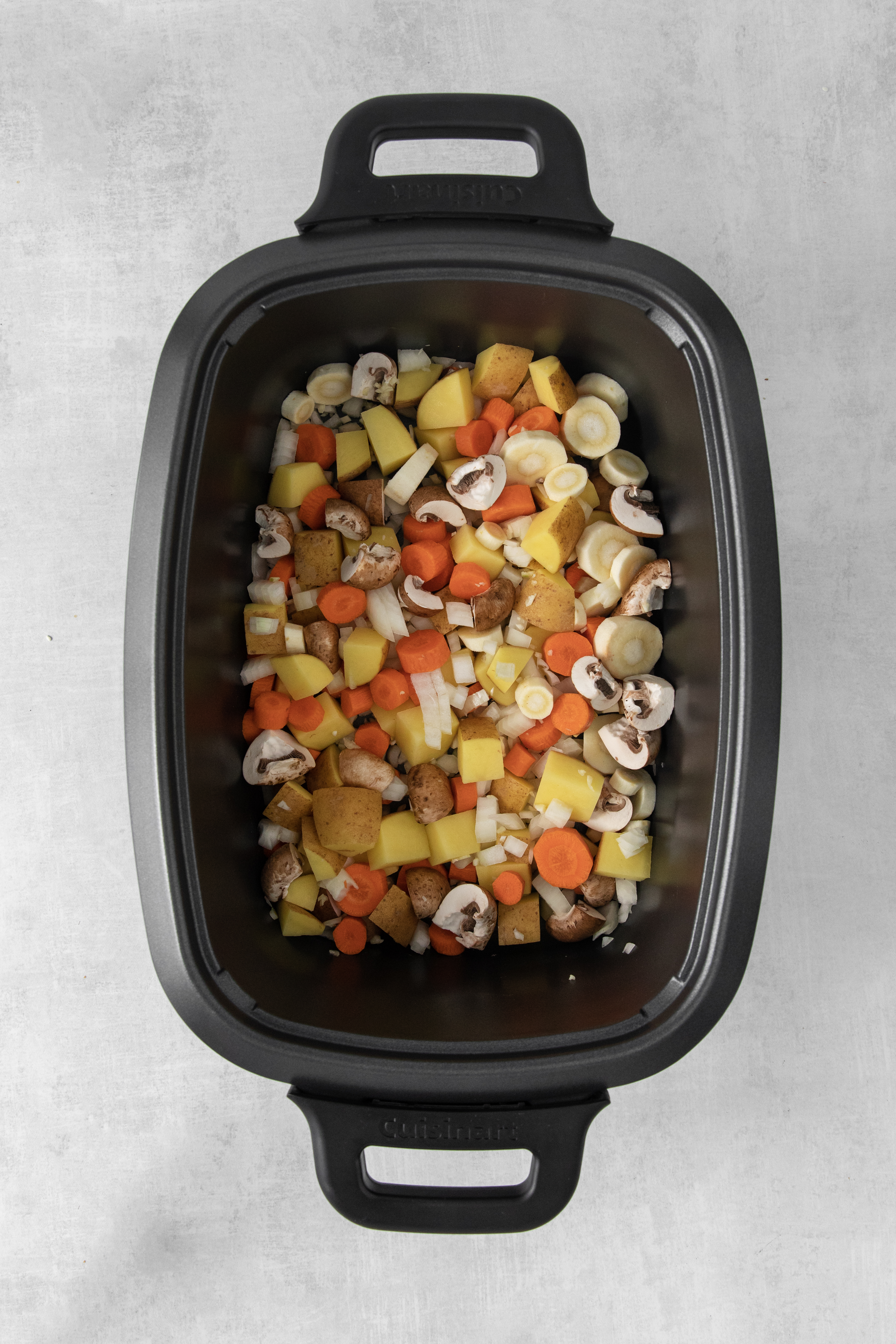 Overhead of stew vegetables in a crock pot.