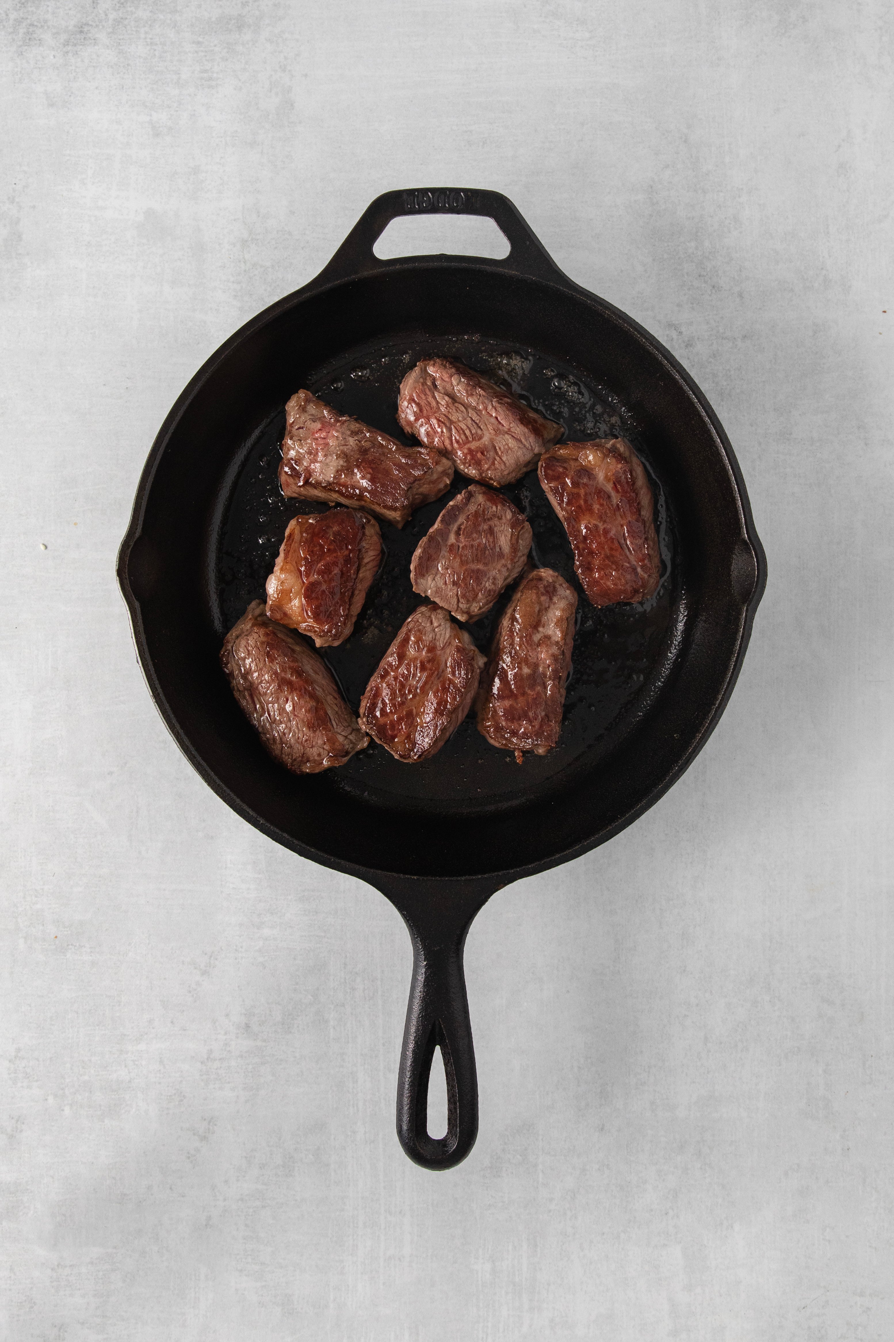 overhead of a skillet with seared cubes of beef.