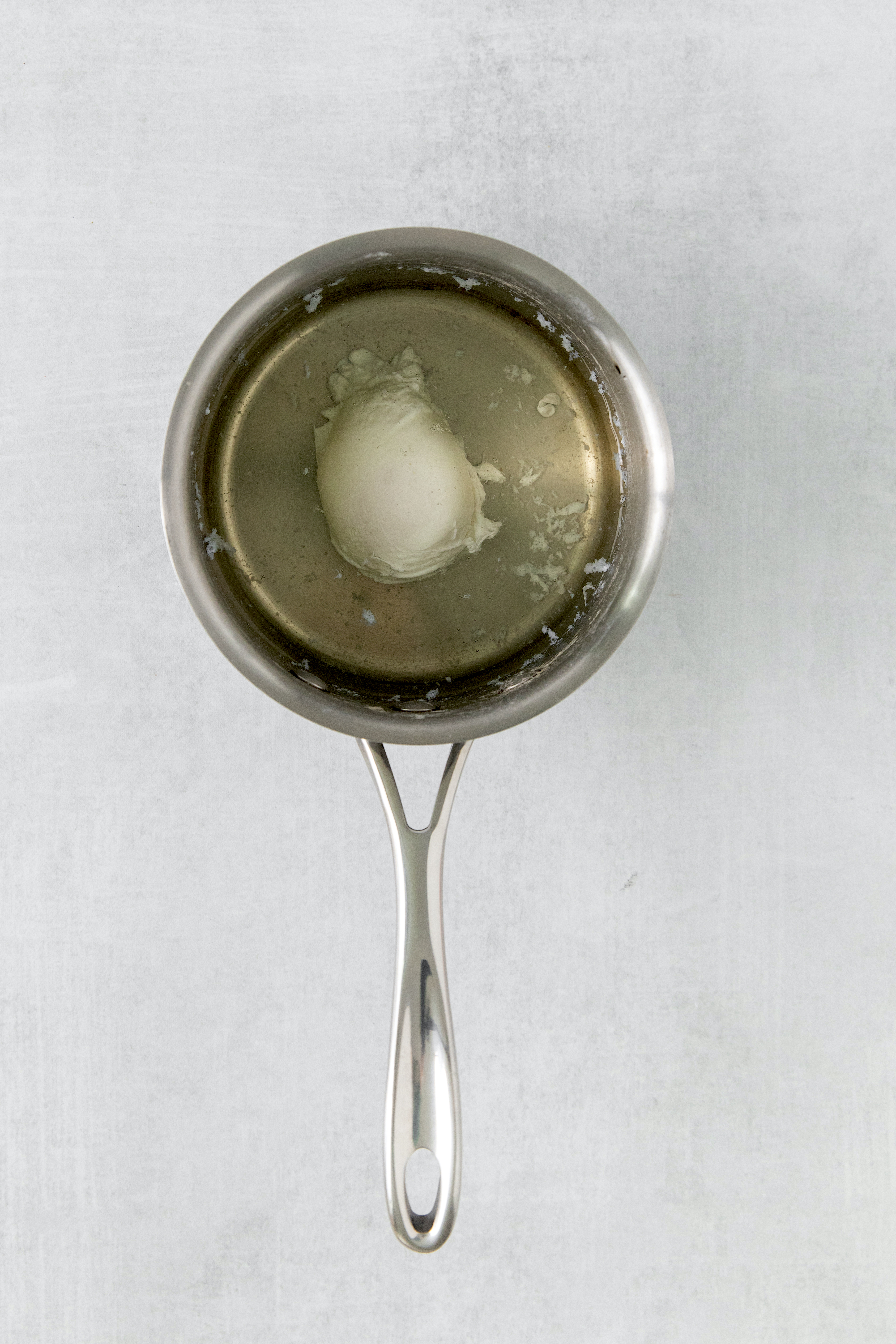 an egg in a pot of simmering water from above.