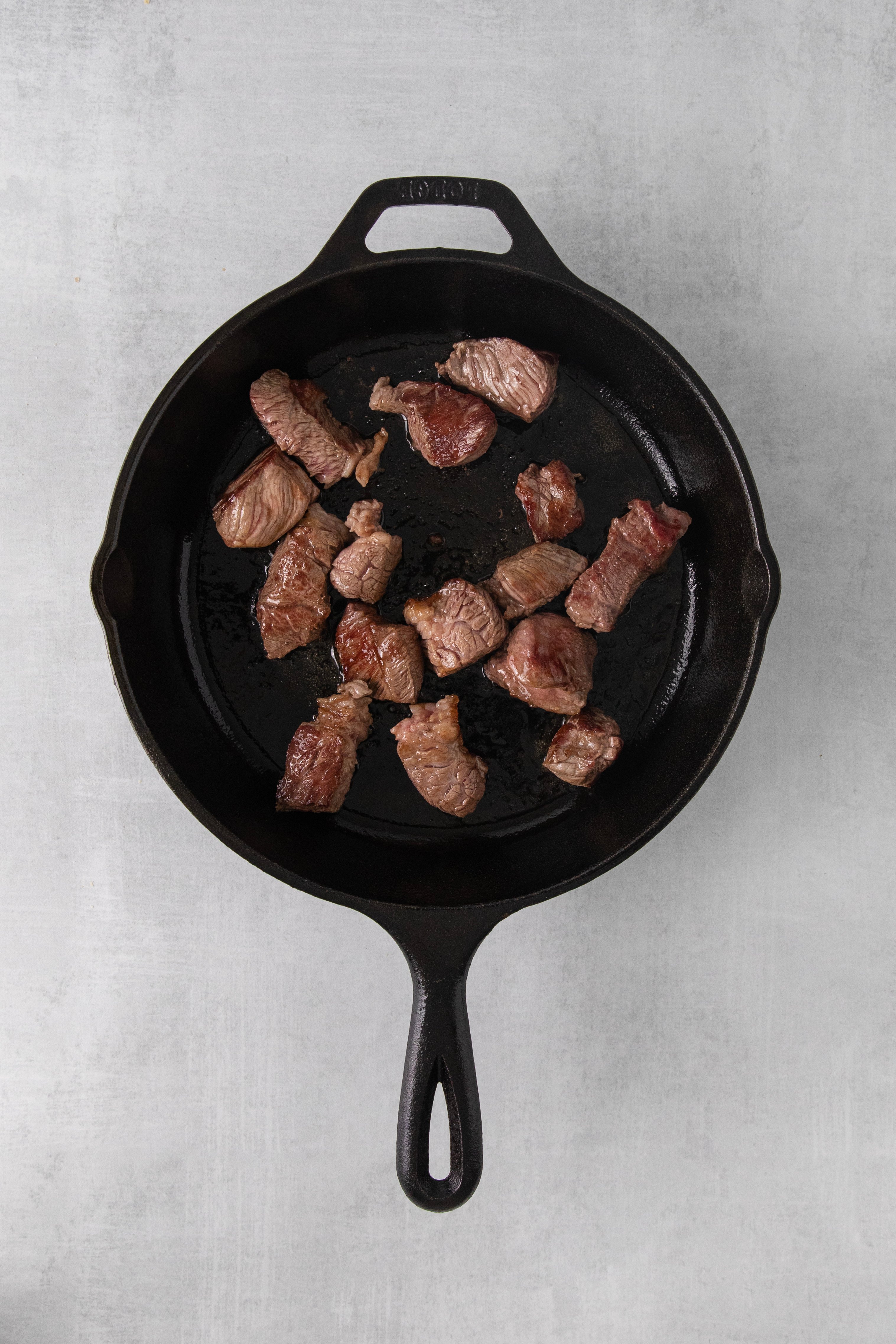 beef being seared in a skillet.