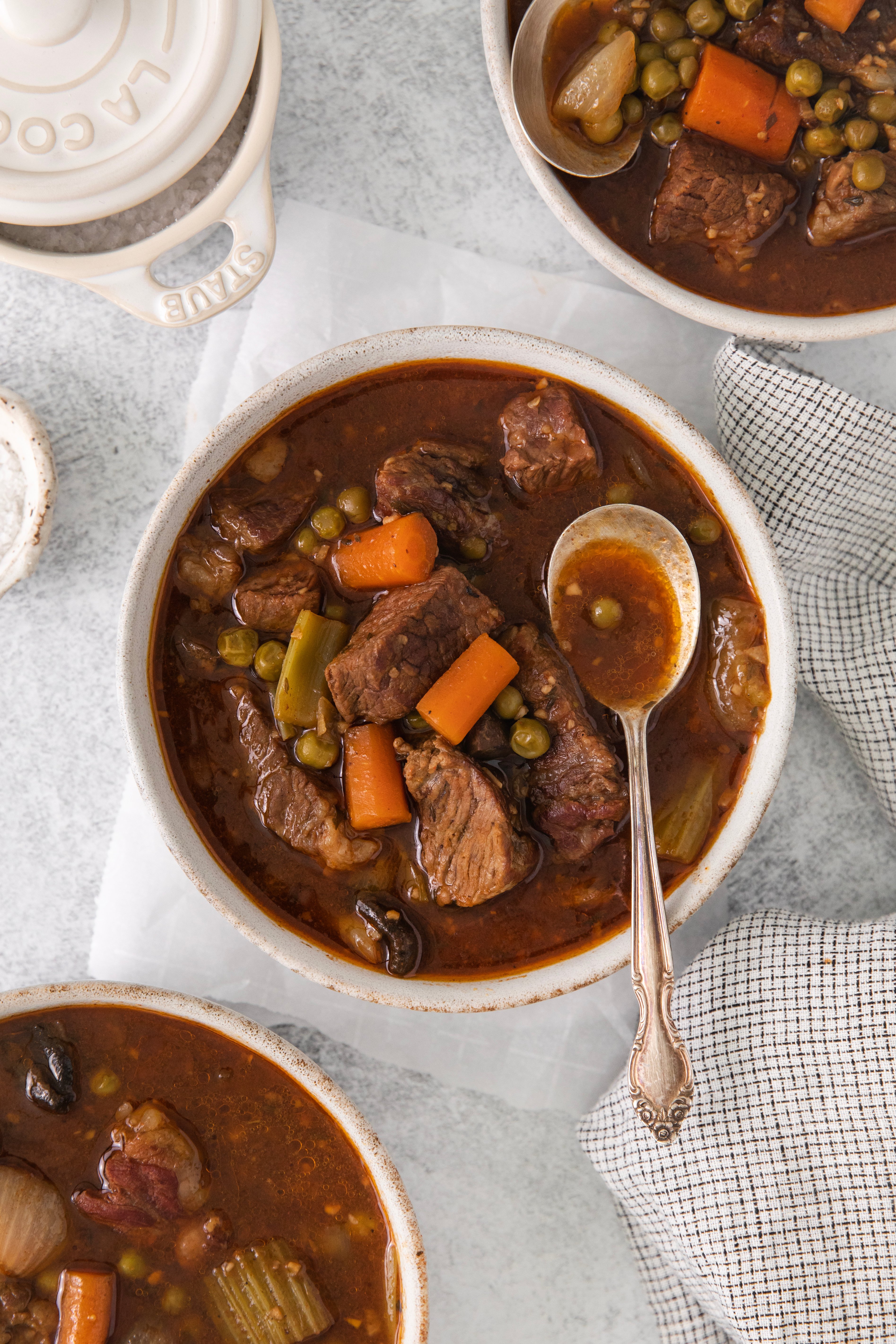 overhead of a bowl of beef stew with a spoon on top.