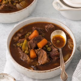 a bowl of beef stew with a spoon on top.