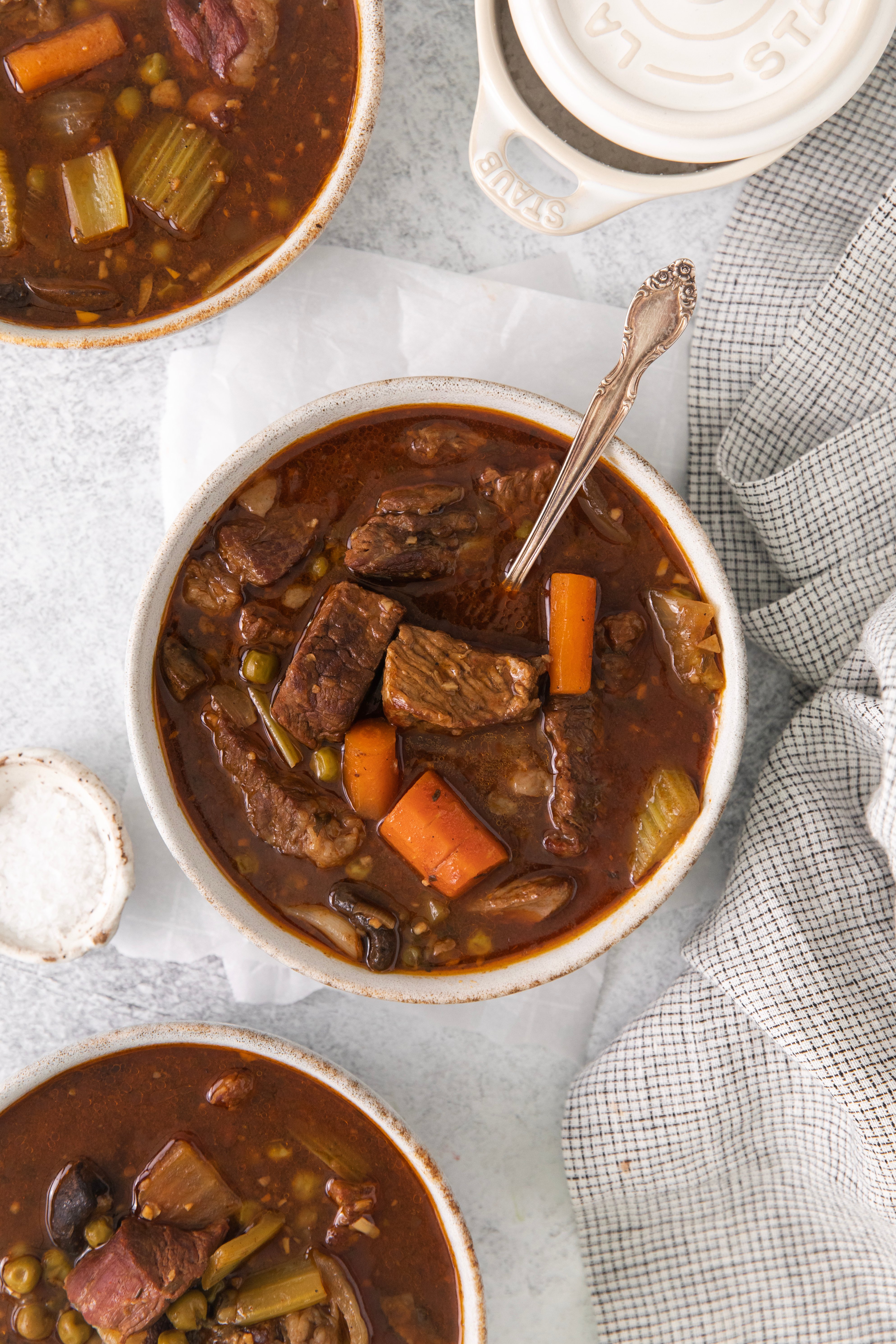 overhead of a bowl of Irish stew with a spoon in between two other bowls.