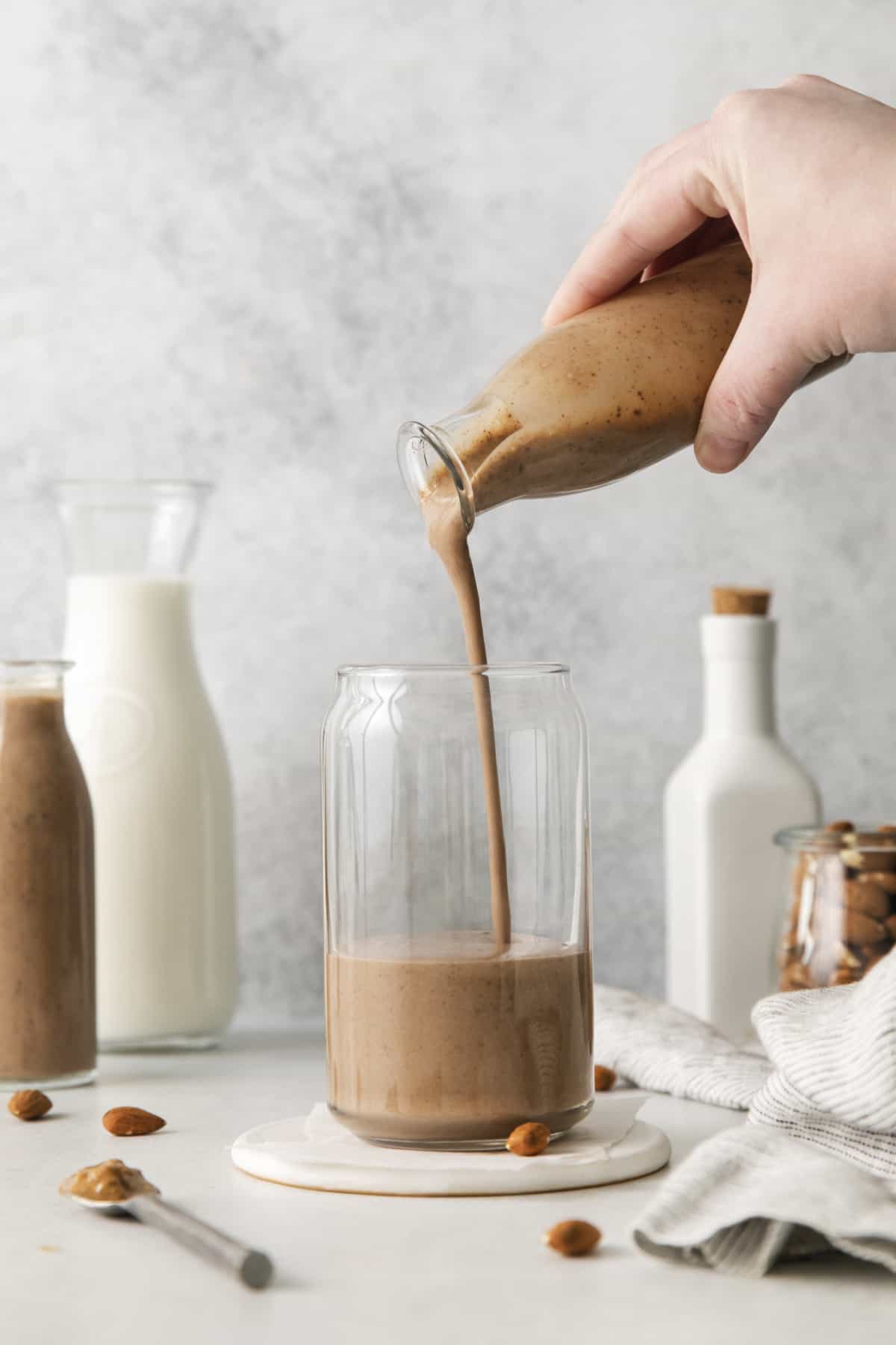 A glass with a smoothie being poured into a mug.