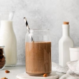 Chocolate banana smoothie in a cup with a straw viewed from the side.