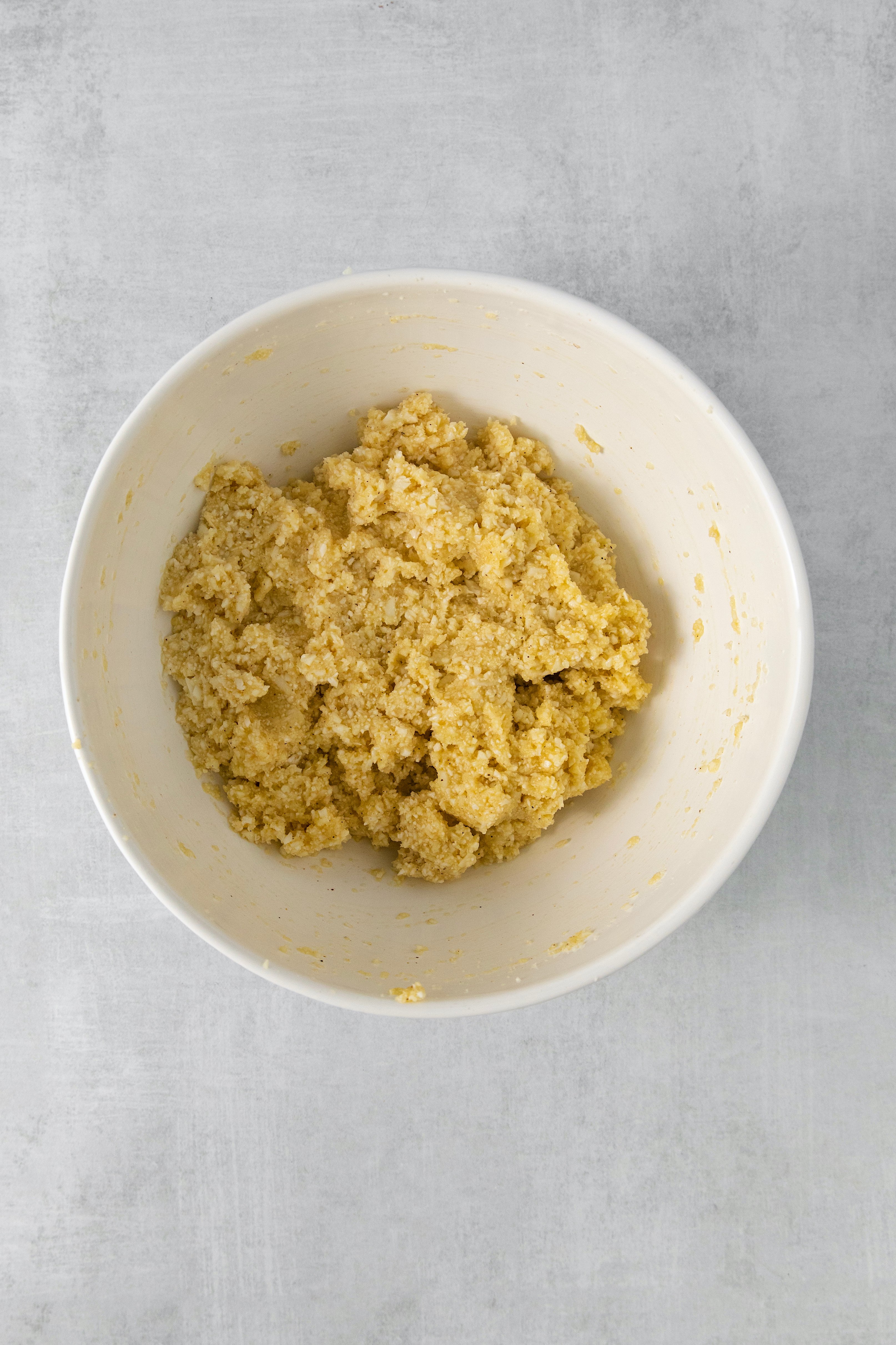 cauliflower, egg, flour, and spices mixed in a bowl.