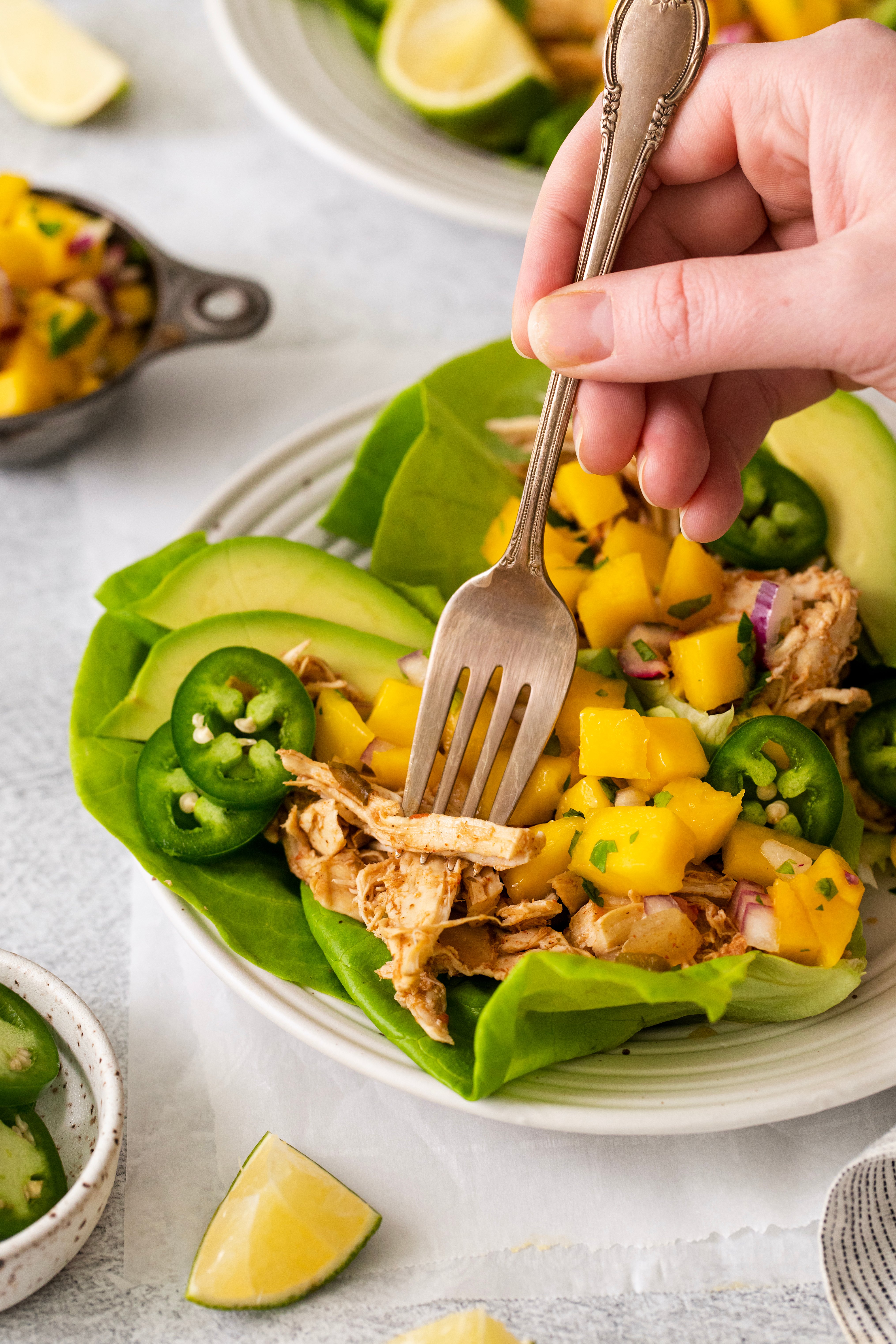 a fork being used to pick shredded chicken out of a lettuce wrap.