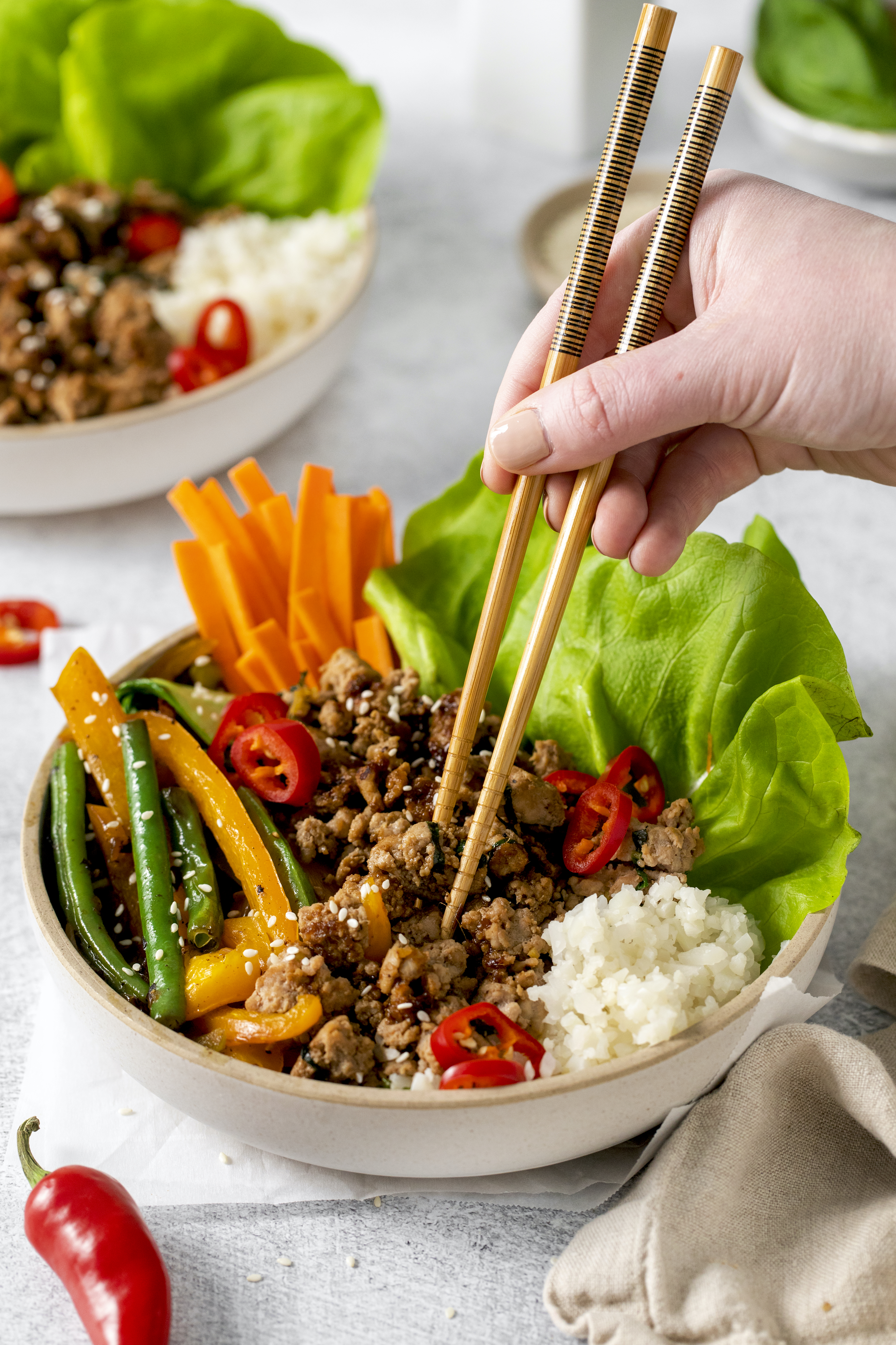 Chopsticks used to pluck ground turkey from a colorful rice bowl.