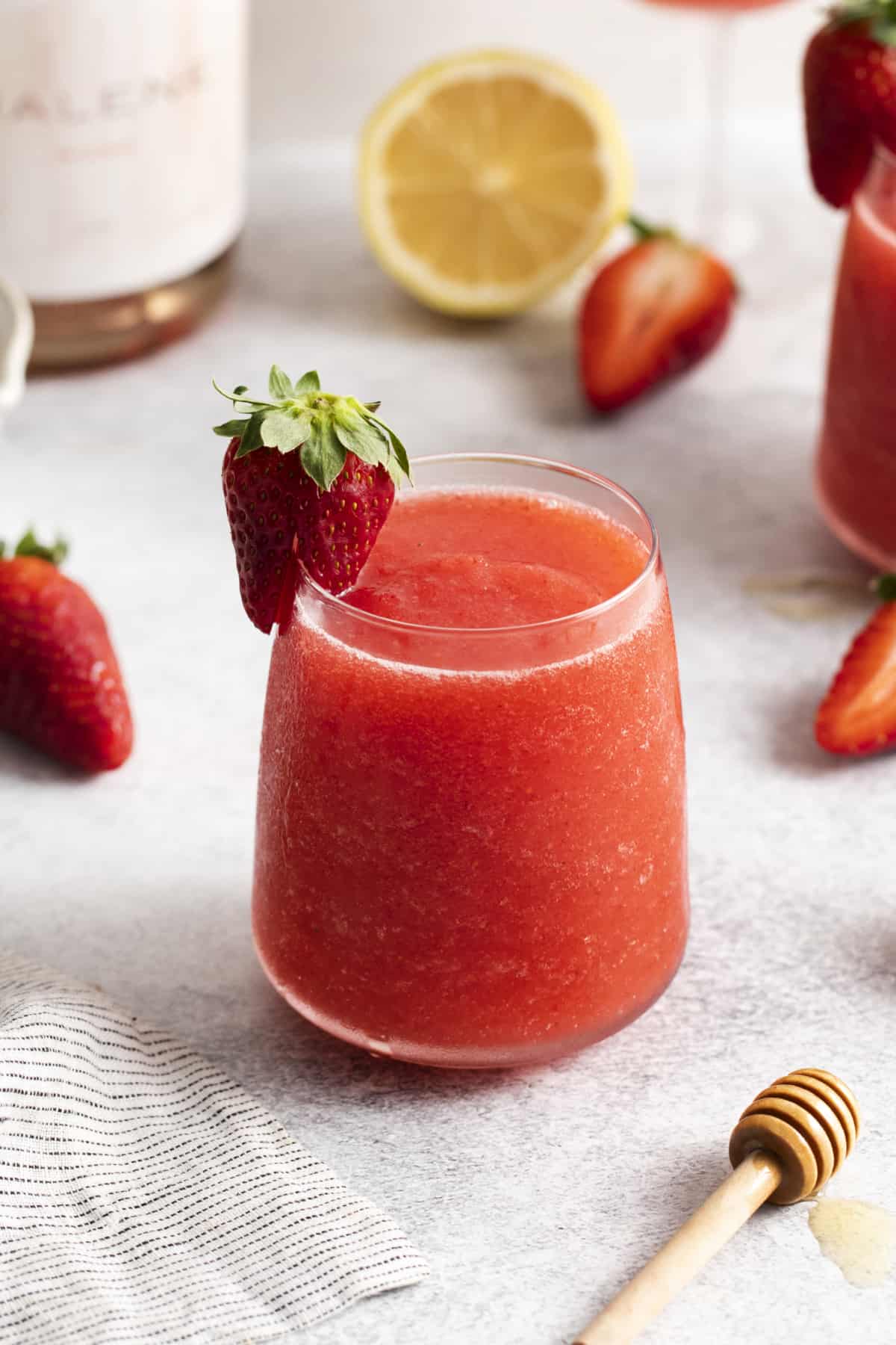 a glass full of frozen wine cocktails garnished with a strawberry.