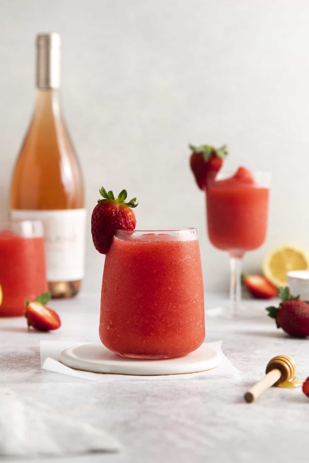 Side view of a glass full of frozen wine garnished with a strawberry.
