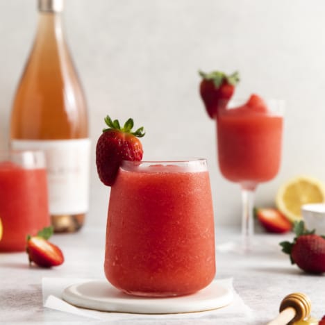 side view of a glass full of a frozen wine slushy garnished with a strawberry.