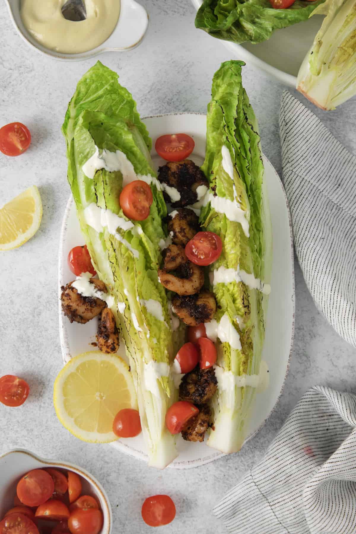 overhead of grilled romaine topped with tomatoes, shrimp, and dressing.