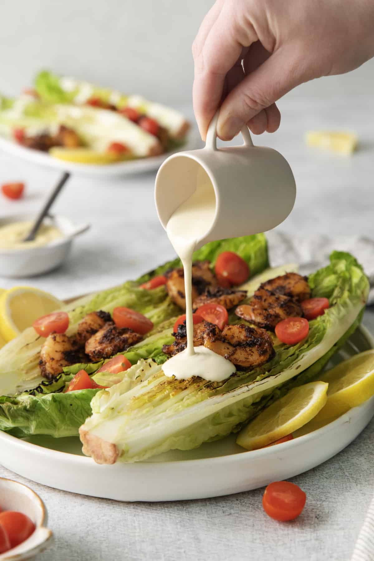 caesar dressing being drizzled over a grilled salad.