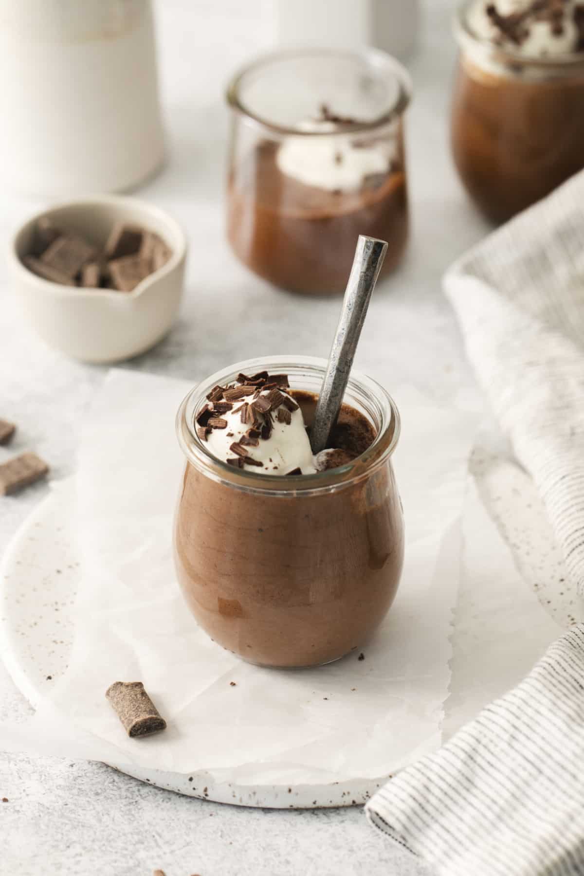 a jar filled with chocolate mousse with a spoon.