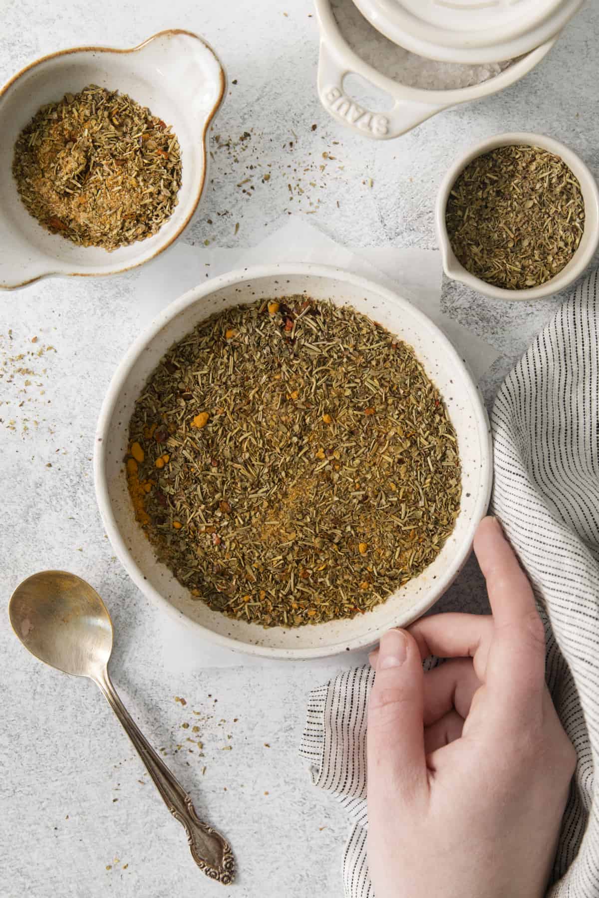 a hand touching a bowl with the best chicken rub.