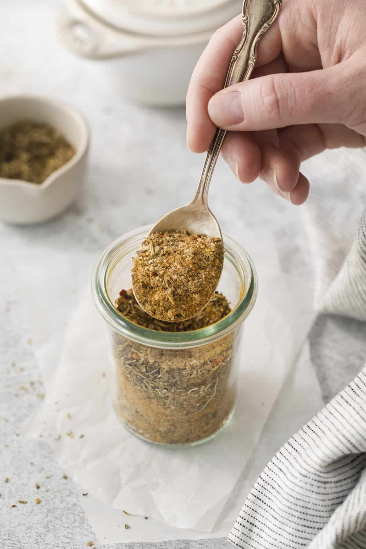 A spoonful of chicken dry grater is scooped out of a jar.