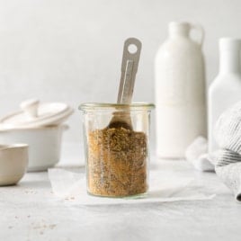 a jar of chicken spice rub with a measuring spoon.