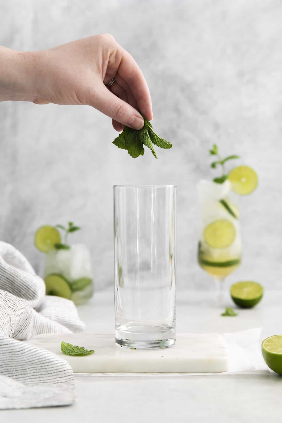 mint leaves being added to a glass.