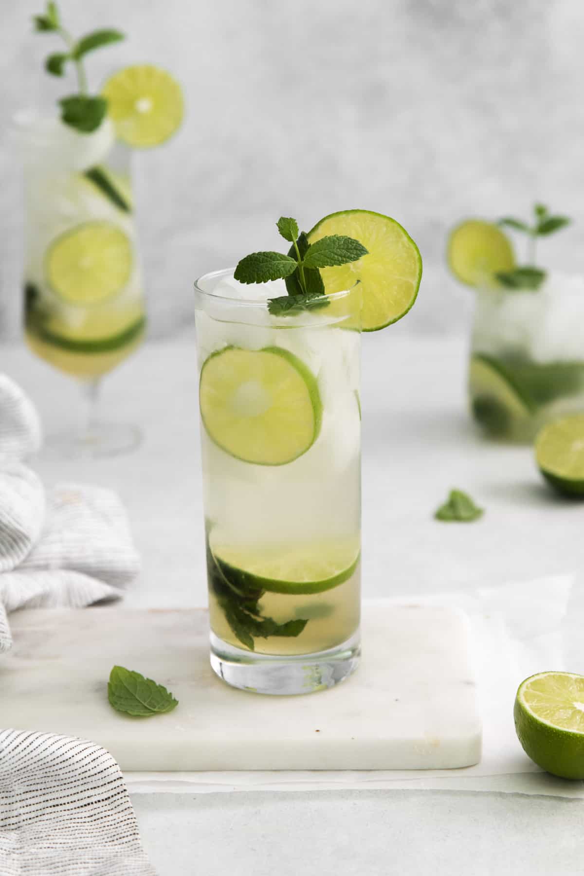 a cup with a mojito and lime and mint garnishes.