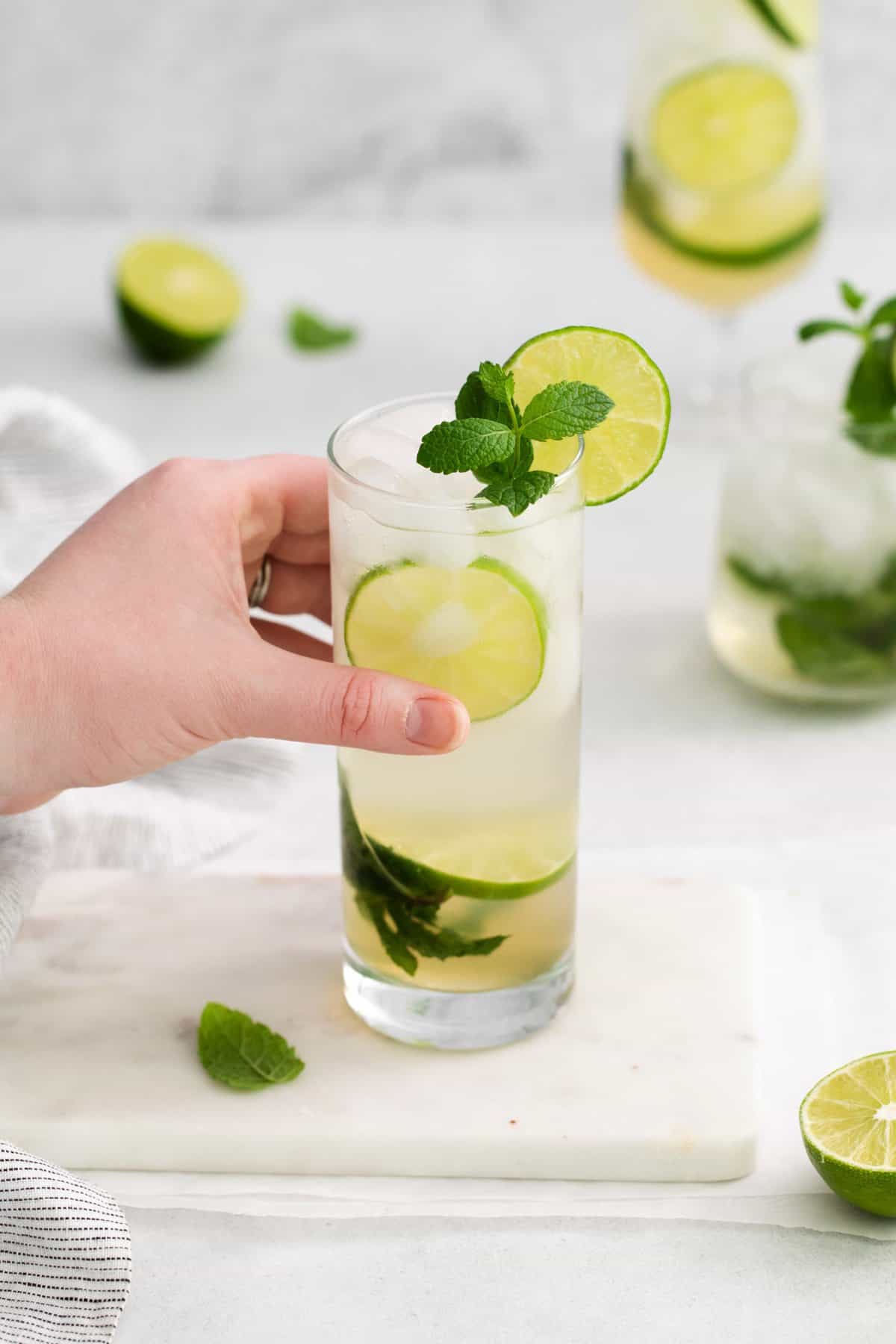 a hand picking up a cup with a mojito.