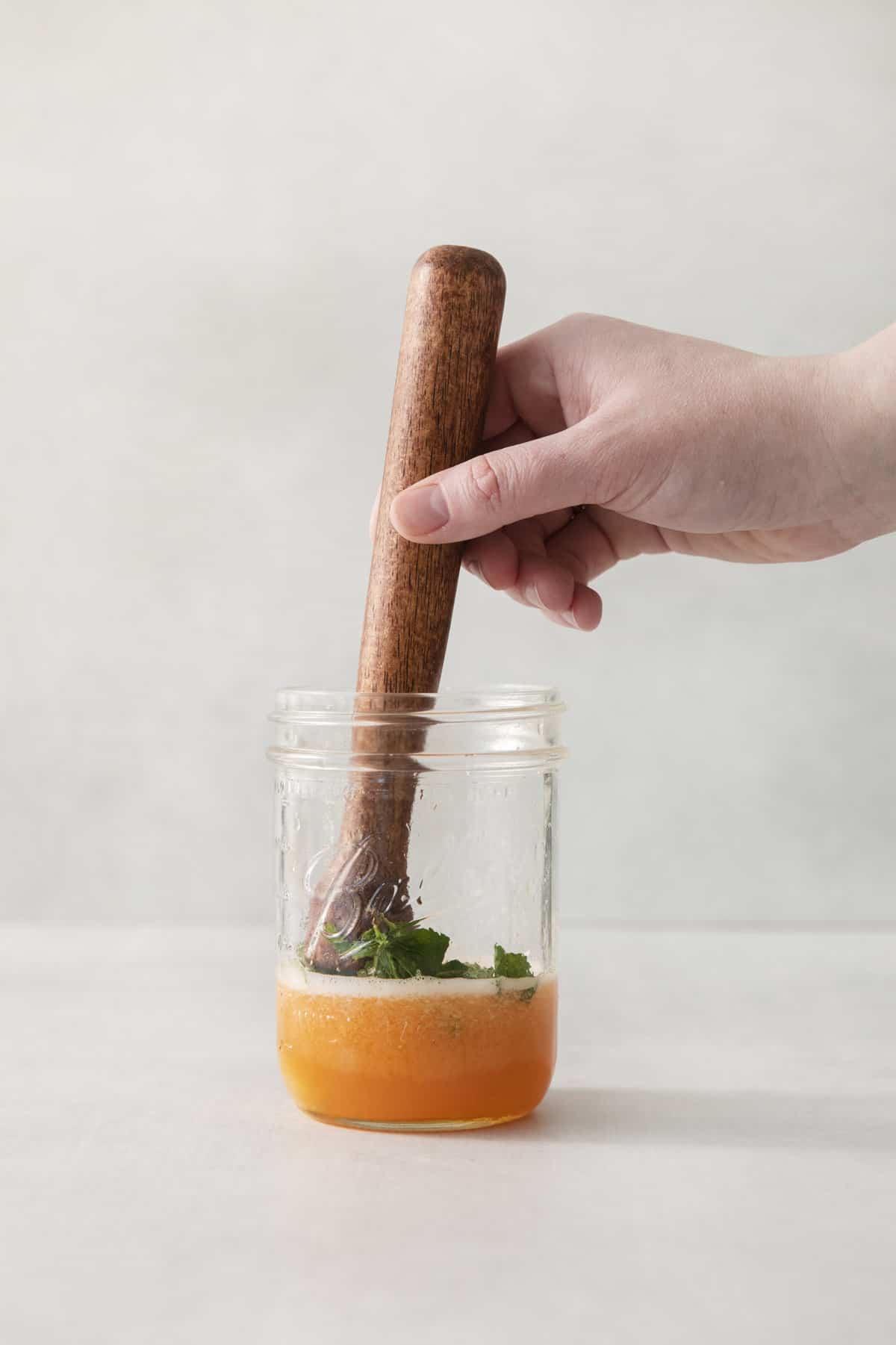 mint leaves being muddled in cantaloupe puree.