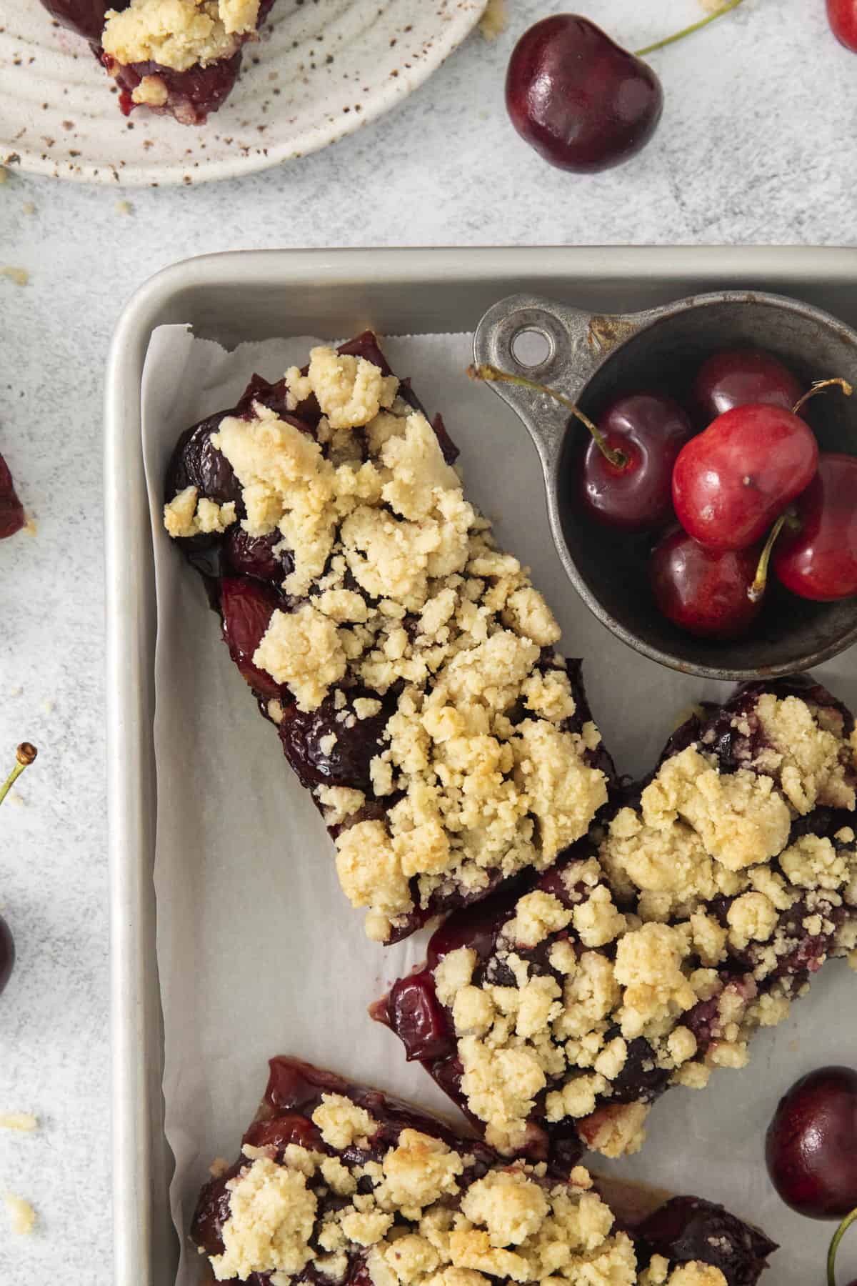 overhead of two pie bars on a tray with a dish of fresh cherries.