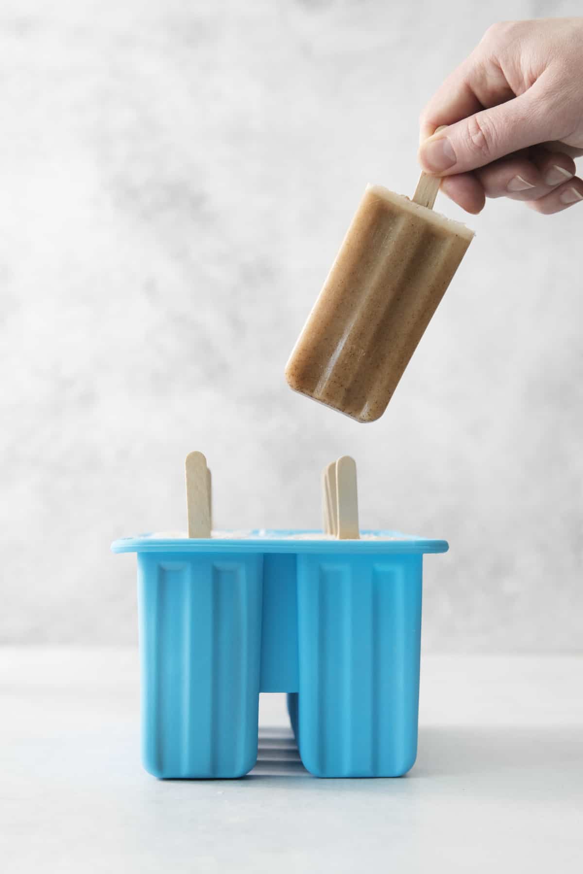 finished chai popsicles being taken out of a popsicle mold.