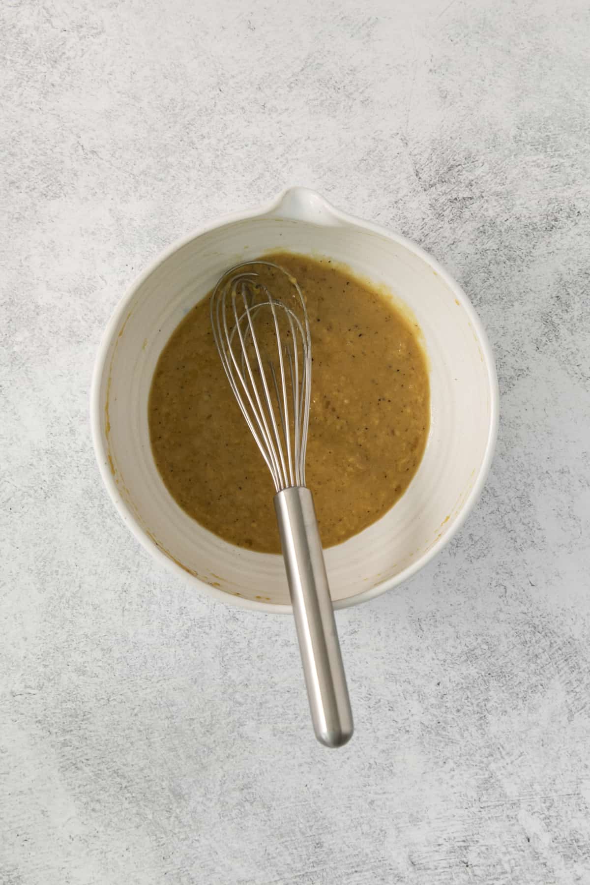 a whisk set in a bowl of homemade dressing.