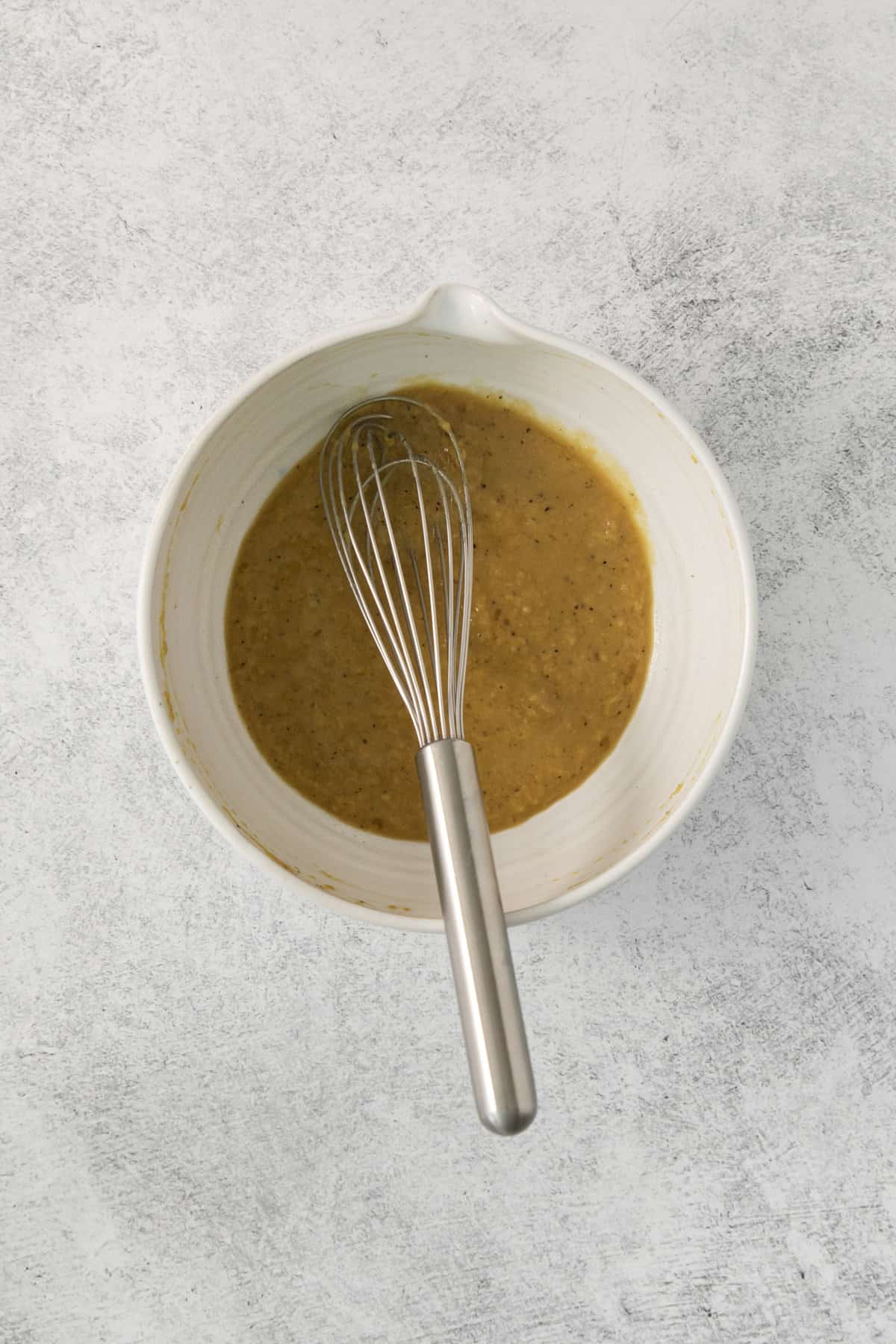 a whisk set in a bowl of homemade dressing.