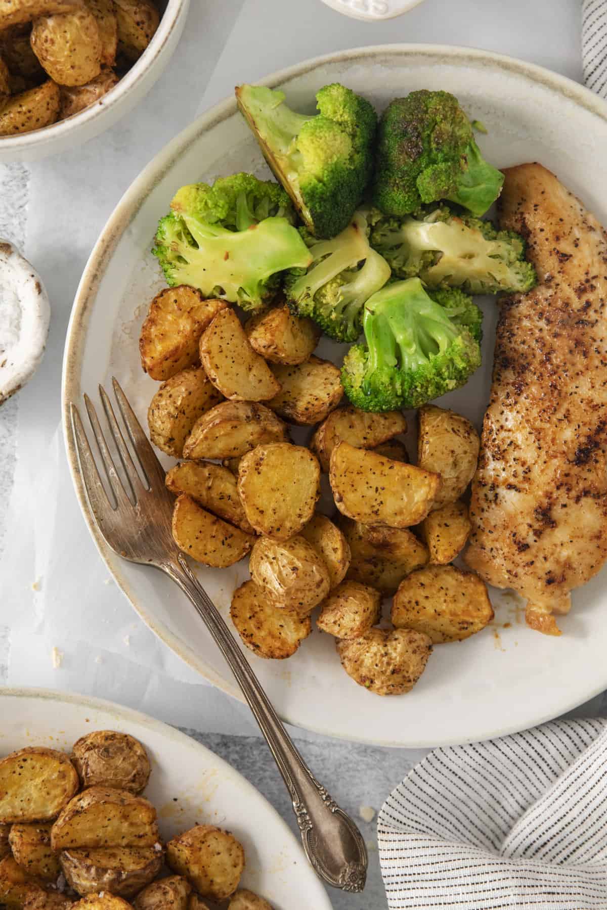 overhead of a plate with air fryer roast potatoes, meat, and broccoli.