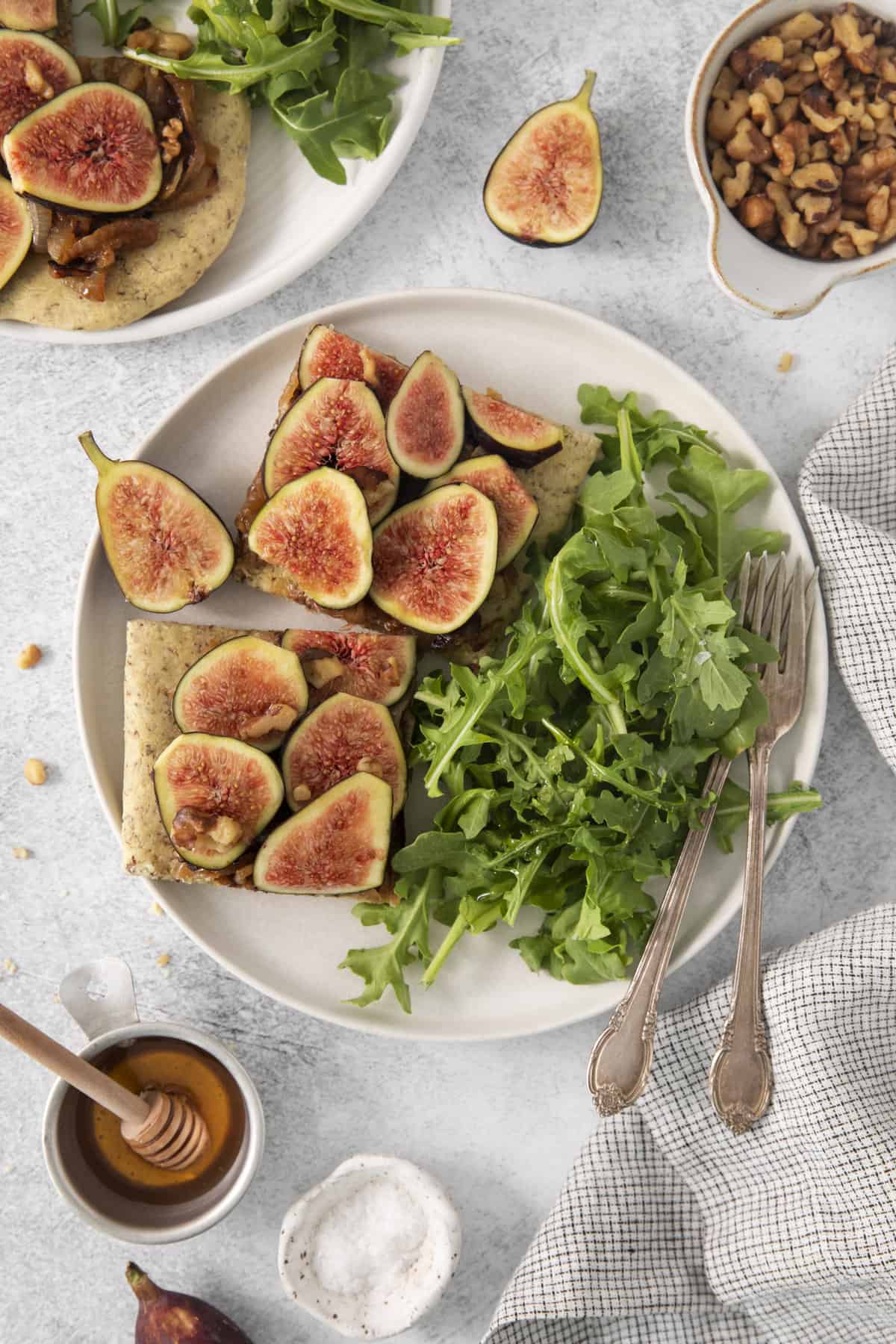 above shot of two slices of fig pizza on a plate with an arugula salad.