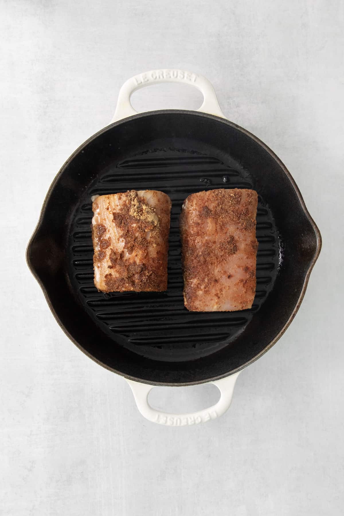 two fish fillets being cooked on a grill pan.