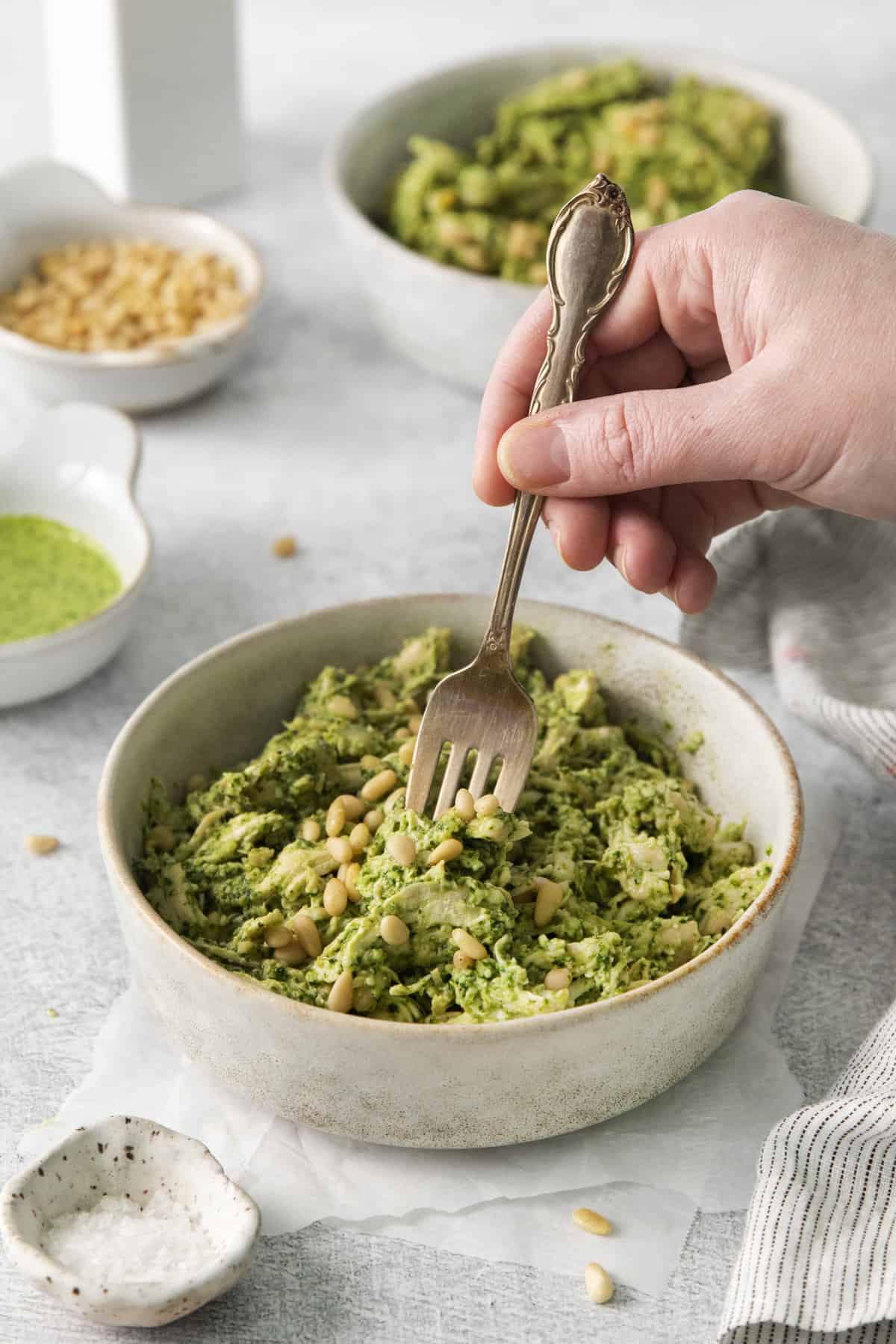 a fork being plunged into a bowl of pesto chicken salad.