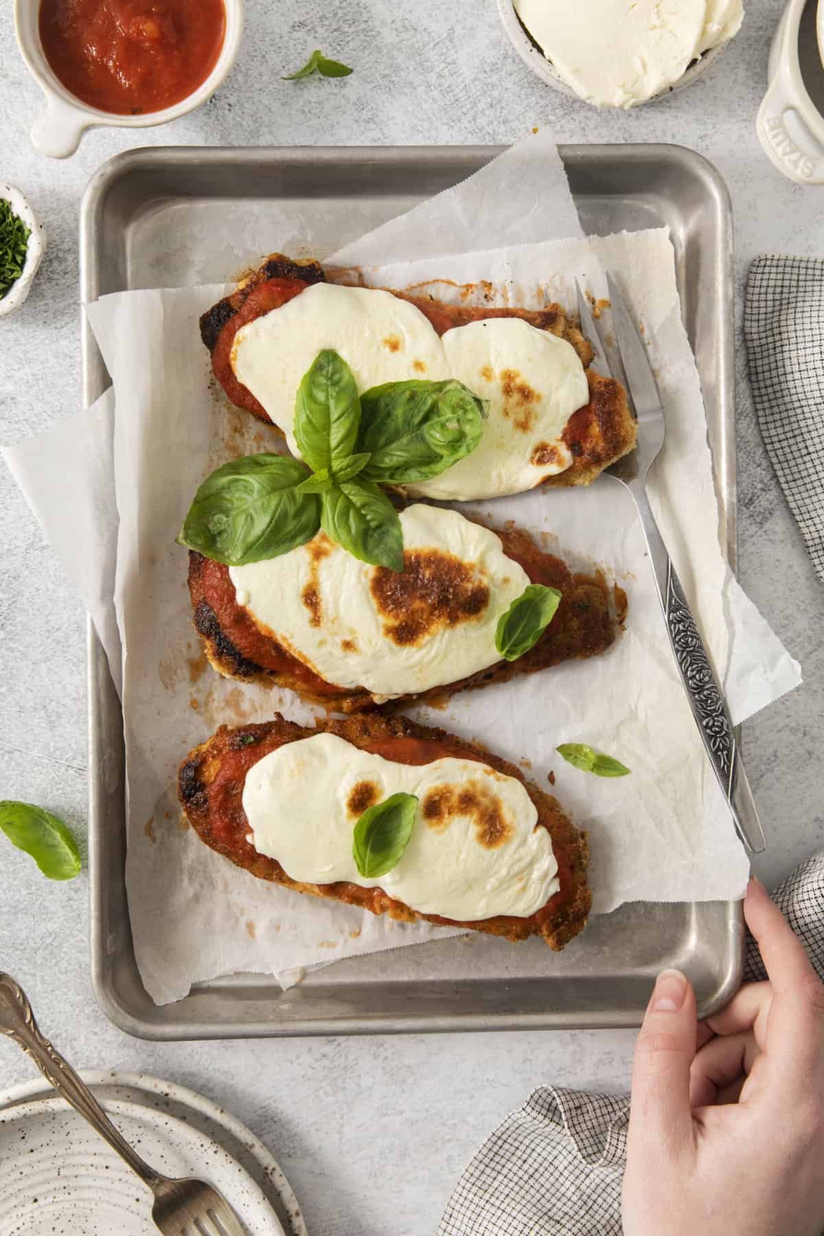 three pieces of chicken parmesan on a baking sheet from above.