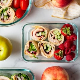 overhead image of containers with pinwheel sandwiches and berries.