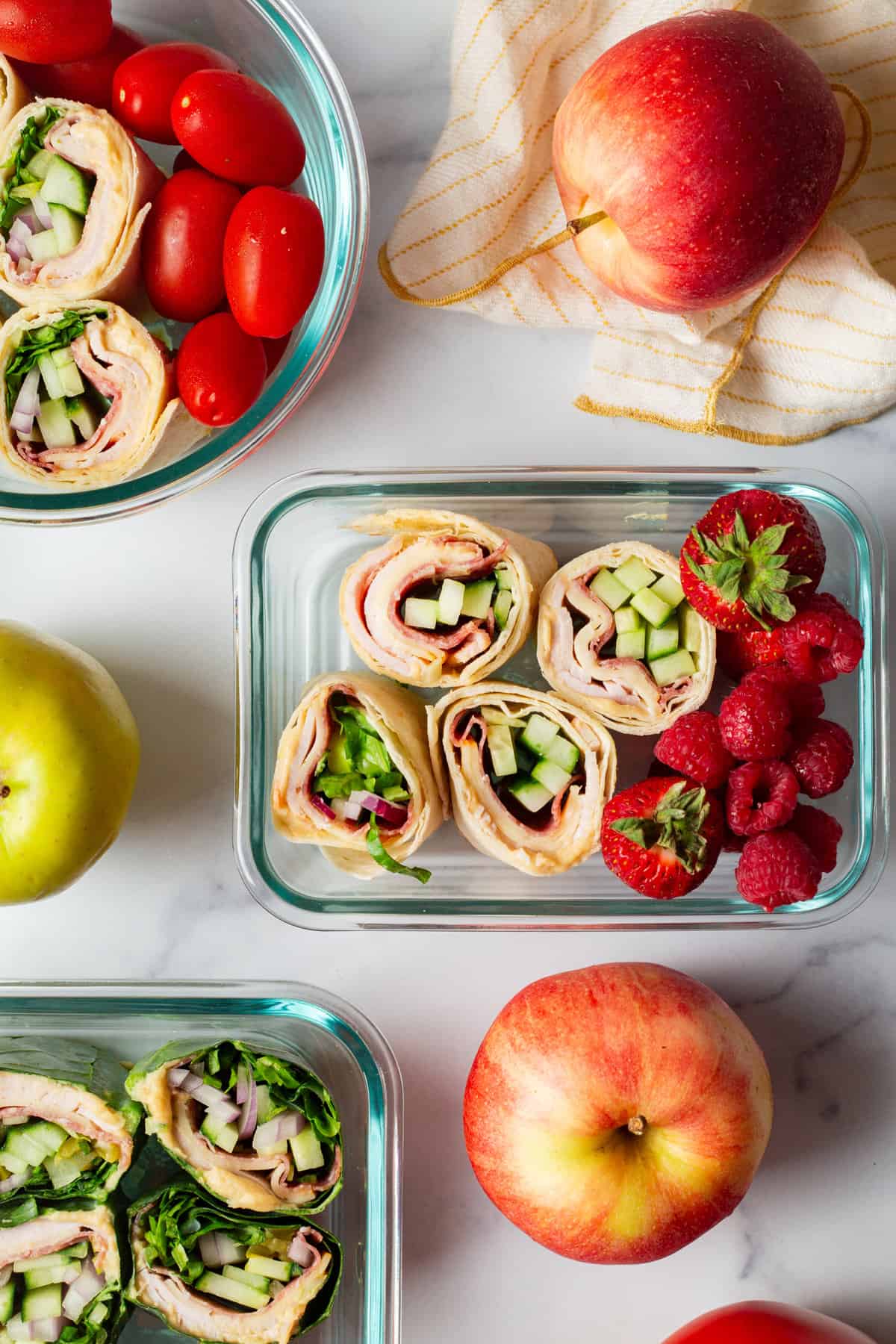 overhead image of containers with pinwheel sandwiches and berries.