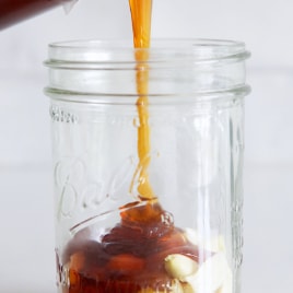 closeup of honey and garlic being poured into a jar.