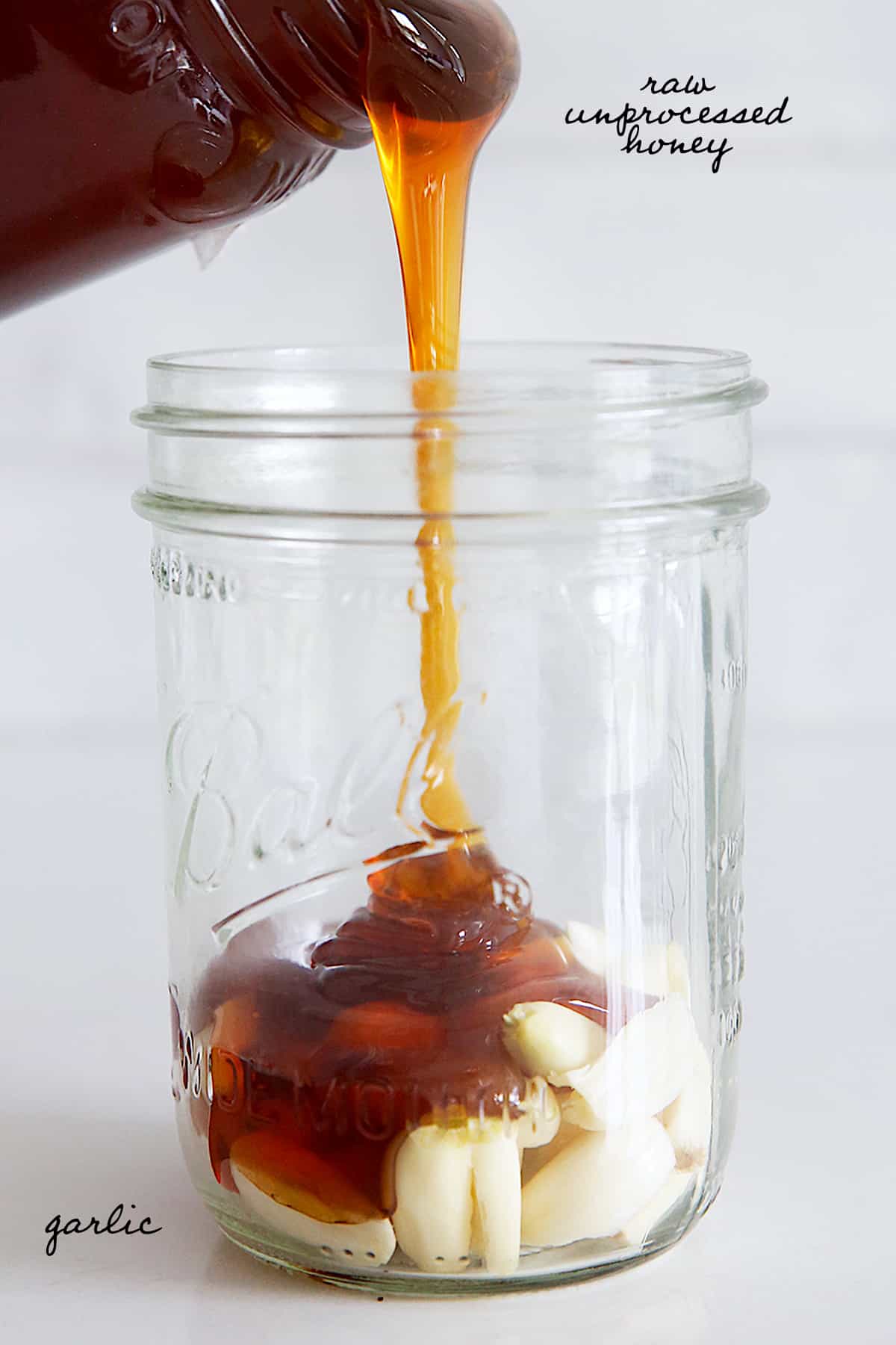 fermented garlic honey being poured int a mason jar with text overlay.
