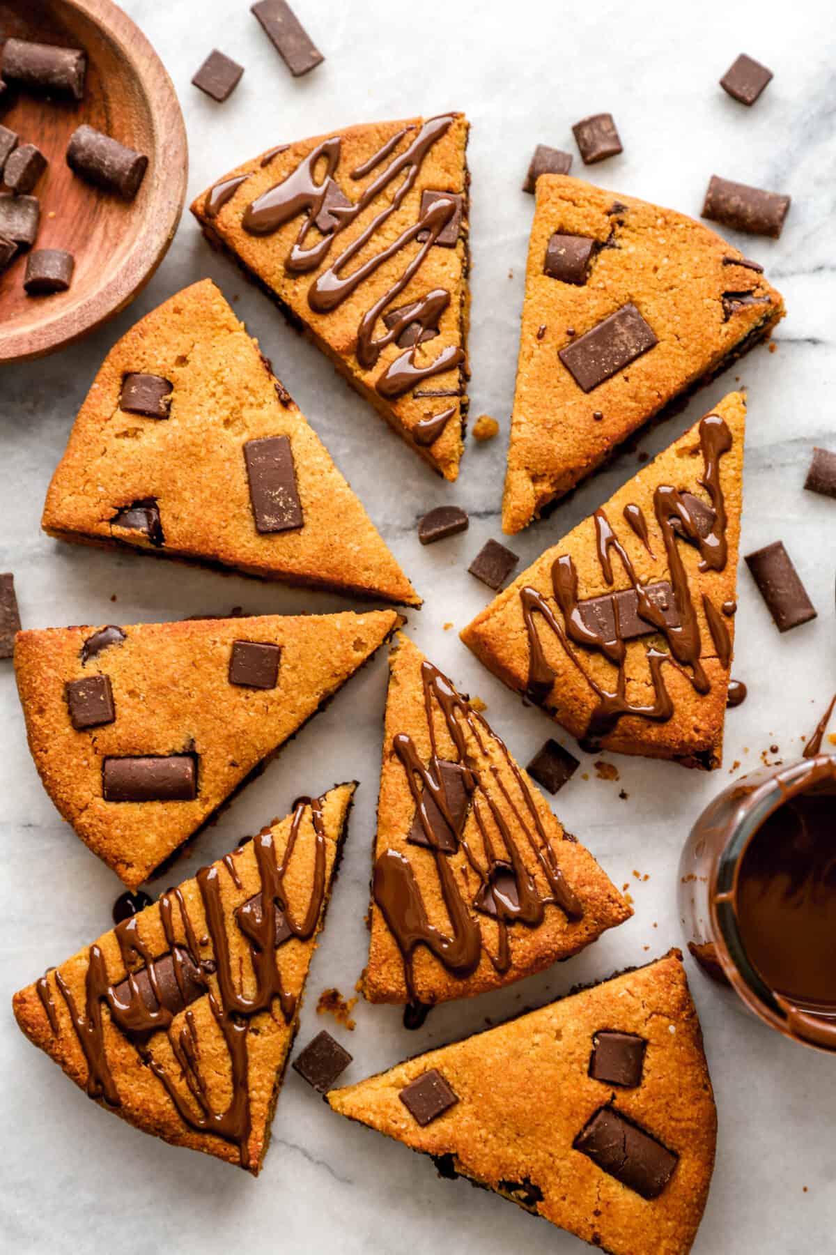 Overhead are paleo pumpkin scones on a cutting board, with chocolate next to the bowl.