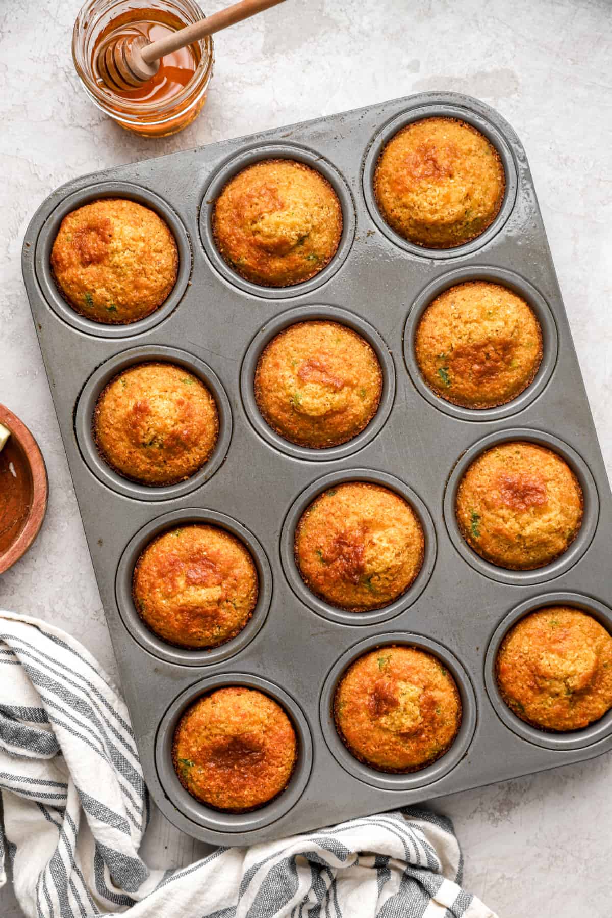 overhead of baked cheddar jalapeno cornbread muffins in a muffin tin.