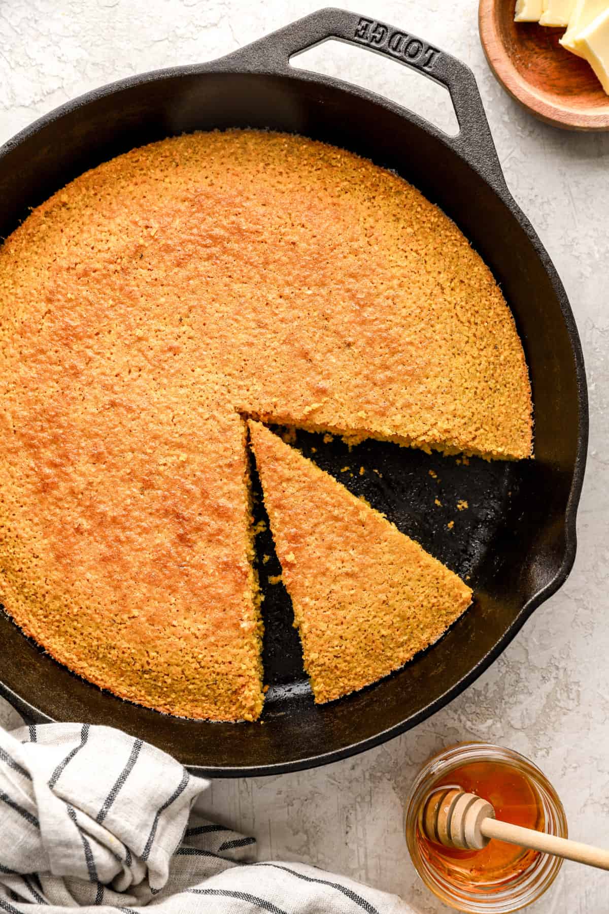 cornbread with a slice cut out in a cast iron skillet from above.