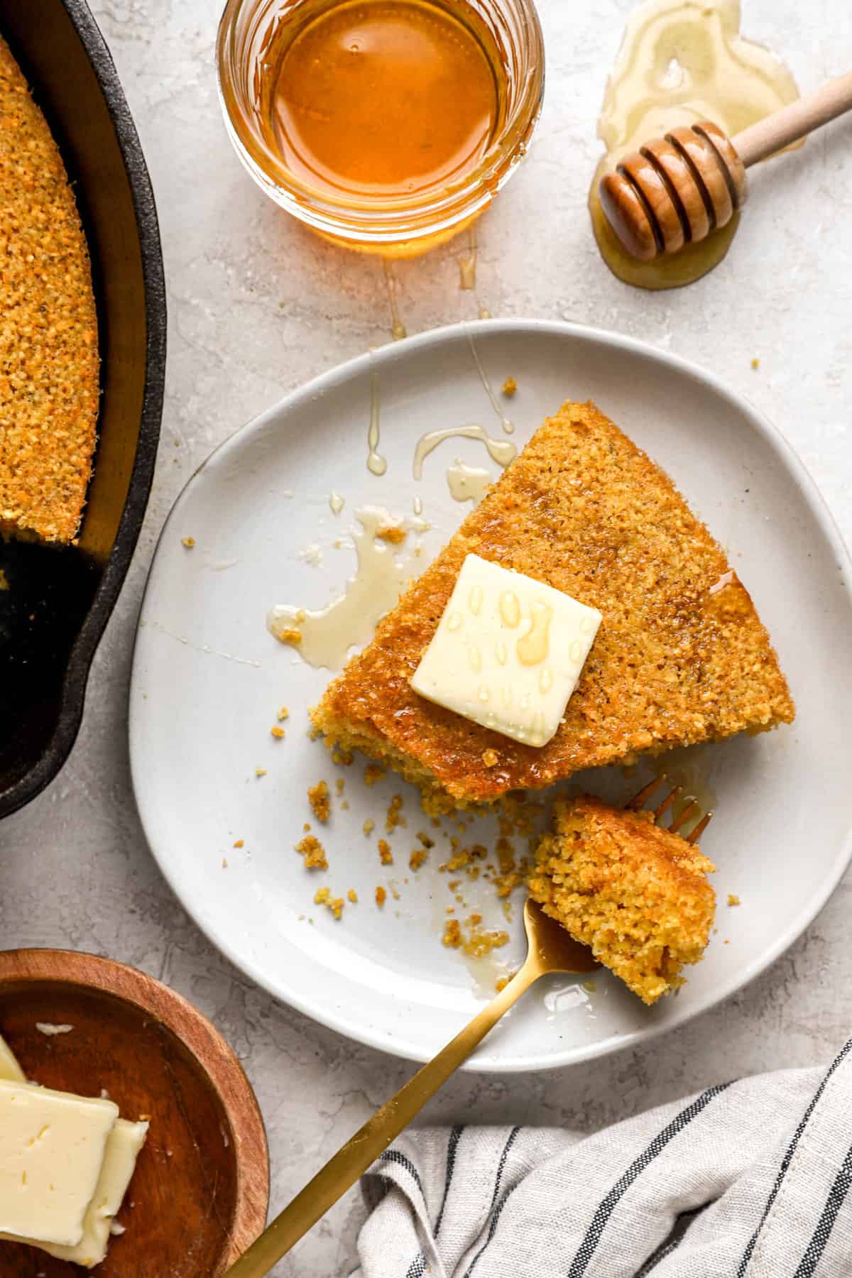 above image of a cornbread wedge with a bite out topped with a pat of butter.