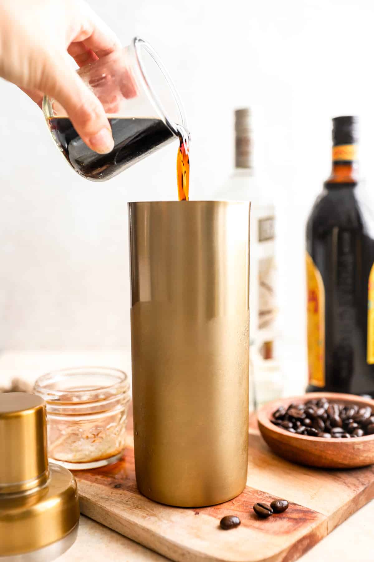 espresso being poured into a cocktail shaker.